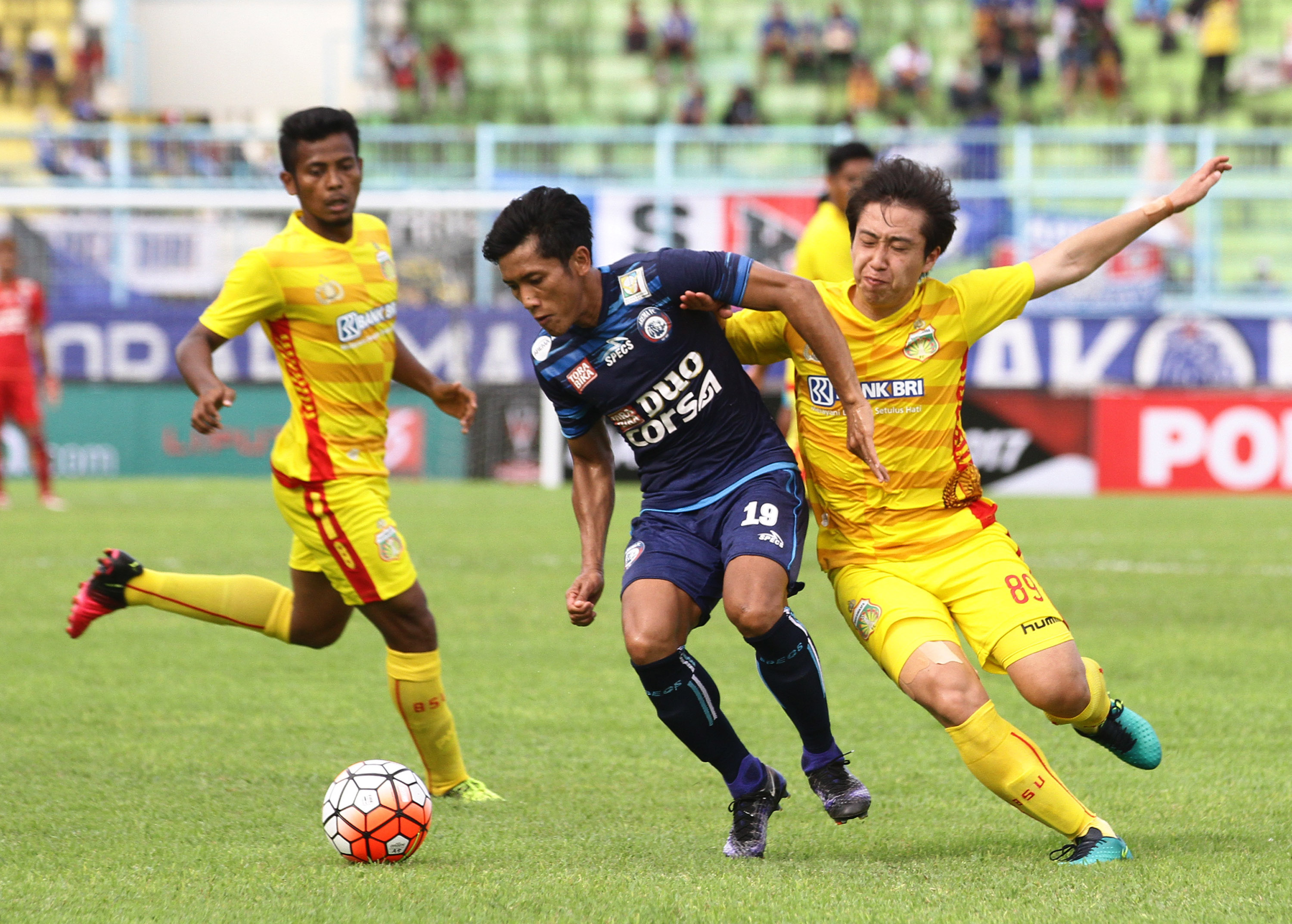 Aksi  pesepak bola Bhayangkara FC Lee Yoo Joon (kanan) dan dan Zulfiandi (kiri) yang membayangi Ahmad Bustomi (tengah). 