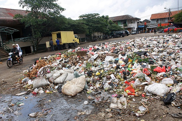 Sejumlah warga tengah melintasi tumpukan sampah yang berserakan akibat tidak beroperasinya Unit Pengolahan Sampah (UPS).