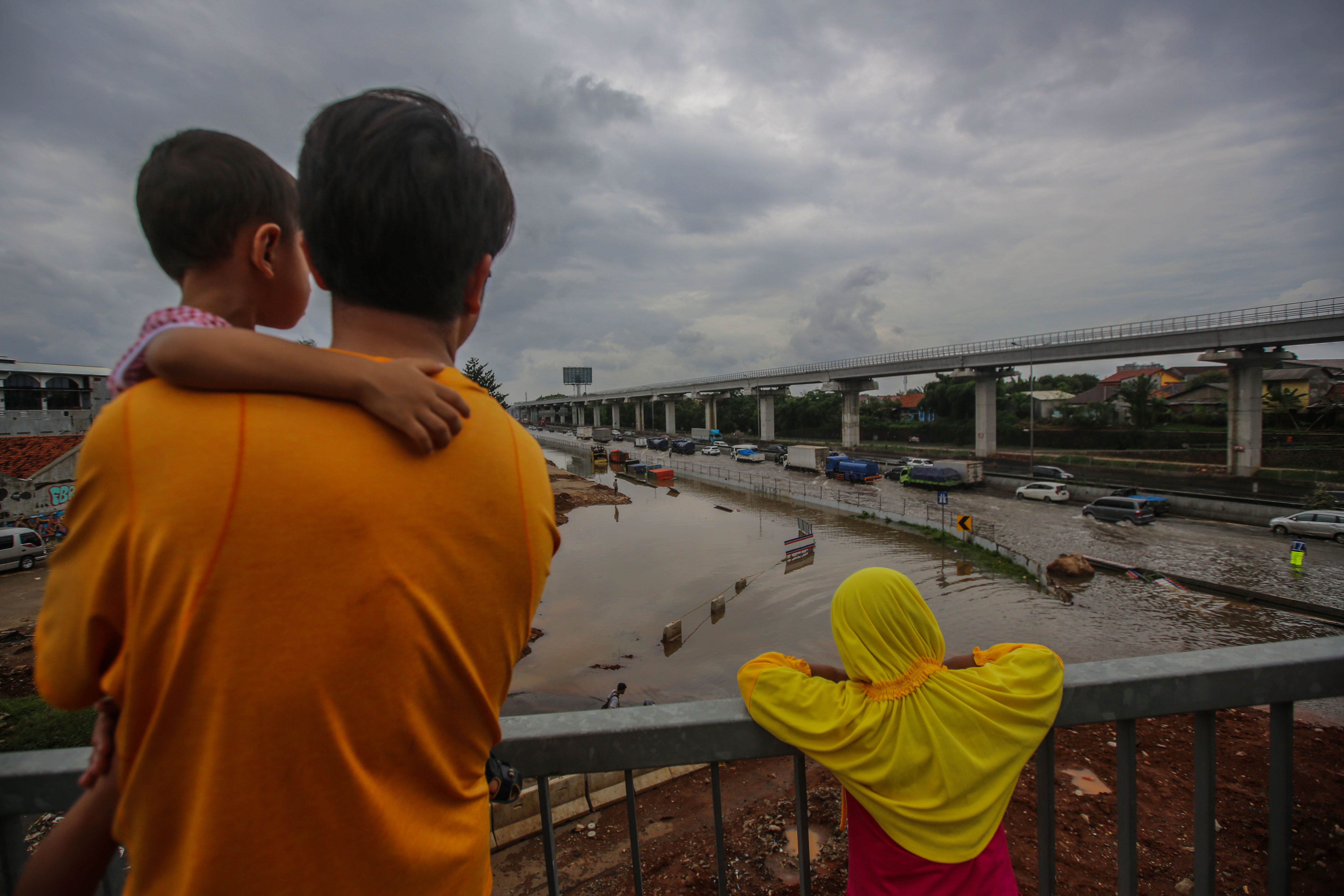 Pengendara memperlambat laju kendaraan saat melewati banjir ruas tol Jakarta-Cikampek kawasan Jatibening, Bekasi, Selasa (25/2).