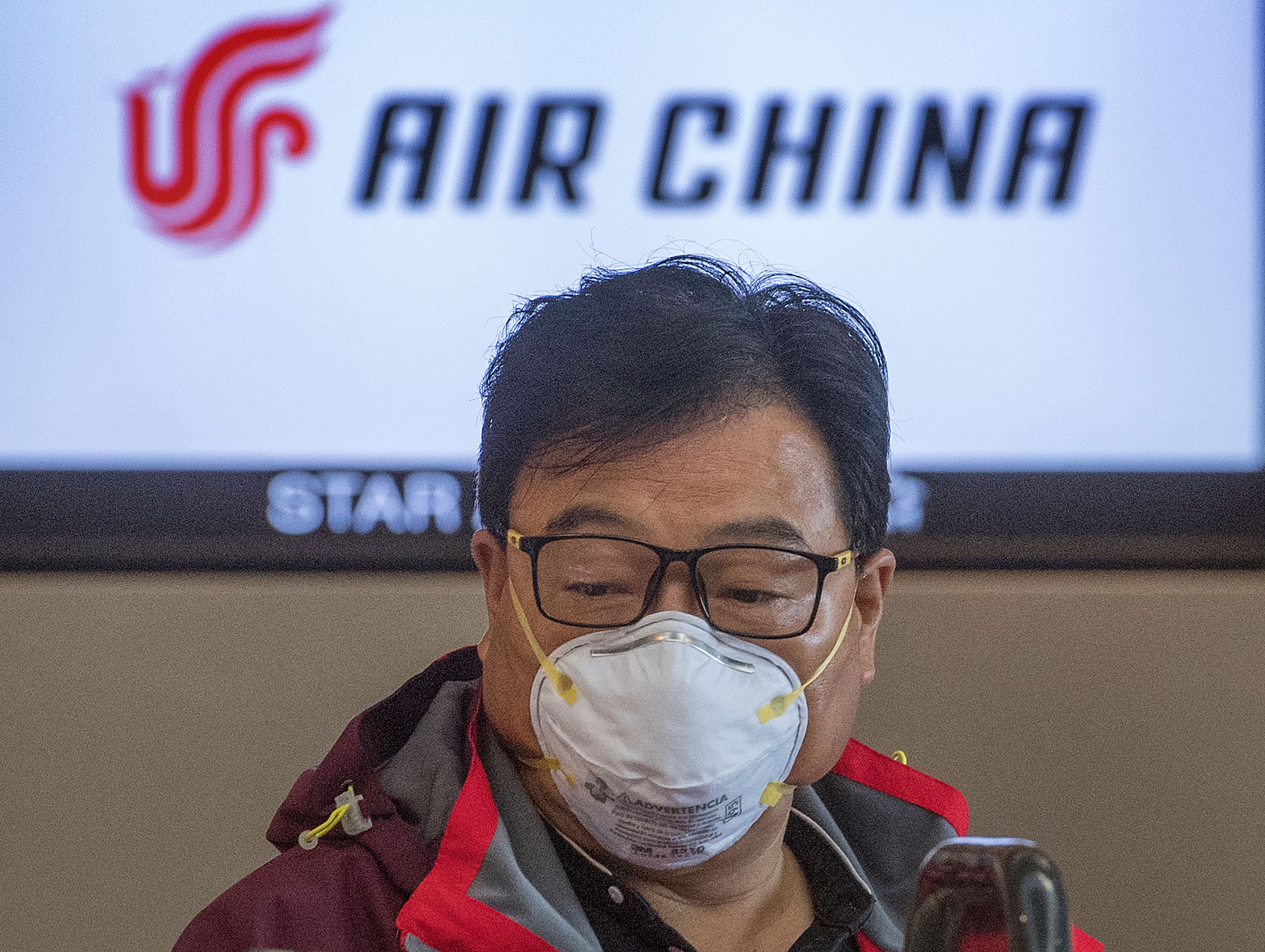 Seorang calon penumpang mengenakan masker melakukan check-in di counter Air China di Los Angeles, California.