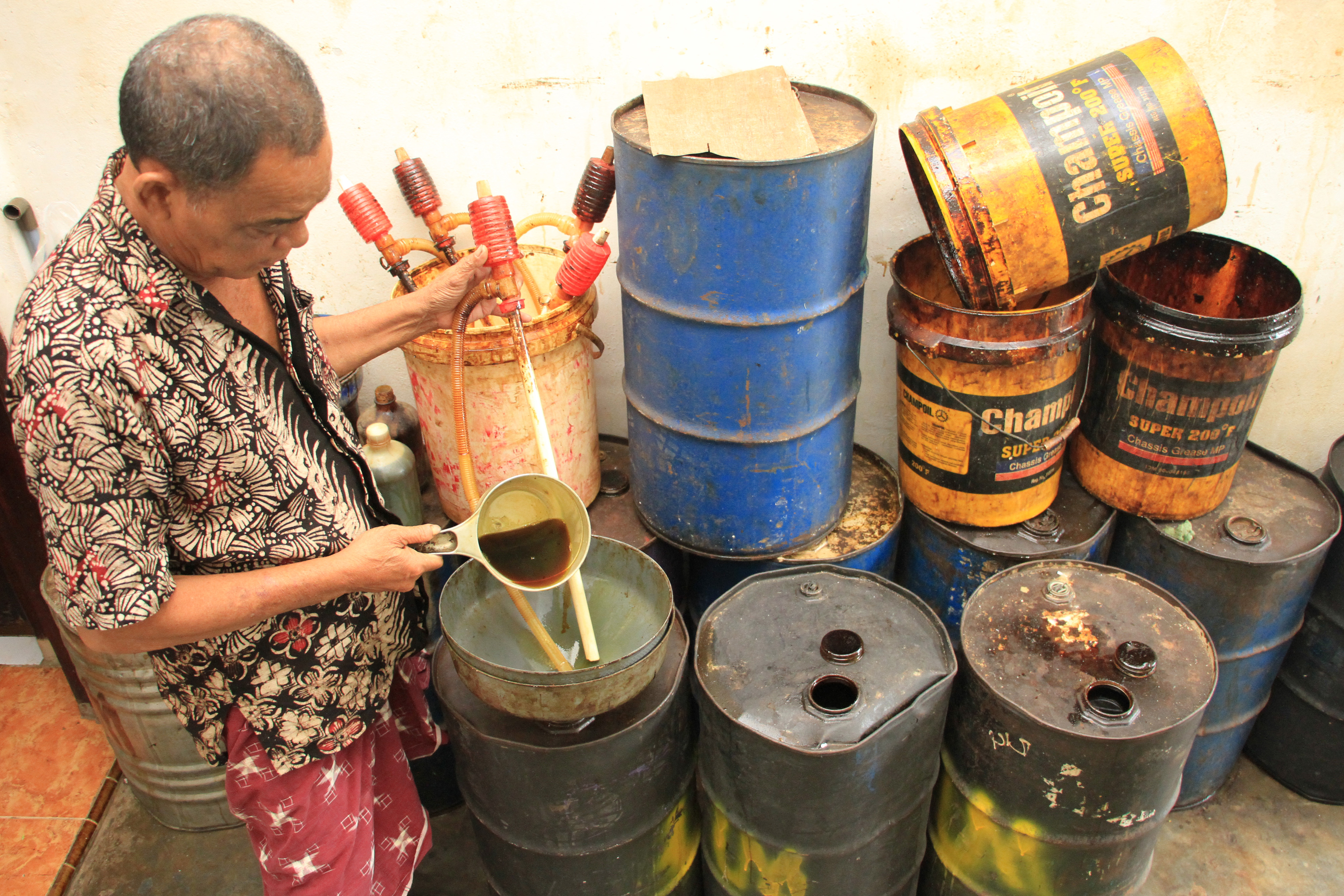 Pedagang menuangkan minyak nilam ke dalam drum untuk proses penyimpanan 