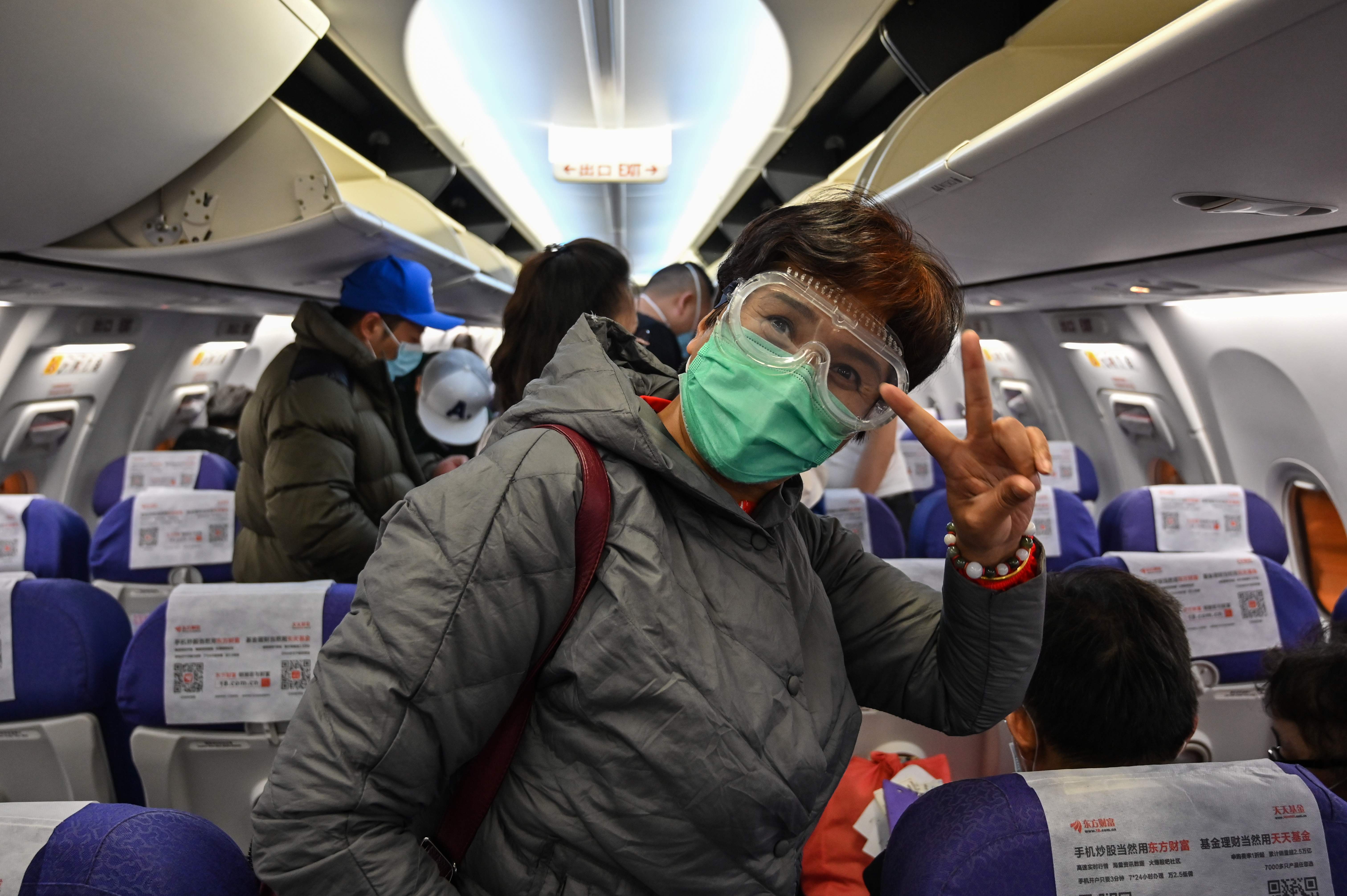 Seorang penumpang mengenakan masker dan pelindung mata berpose saat mendarat di Bandara Internasional Pudong, Shanghai.
