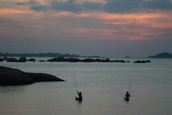 Para nelayan memancing ikan saat matahari tenggelam yang menjadi pesona di Pantai Tanjung Tinggi, Belitung, Bangka Belitung.