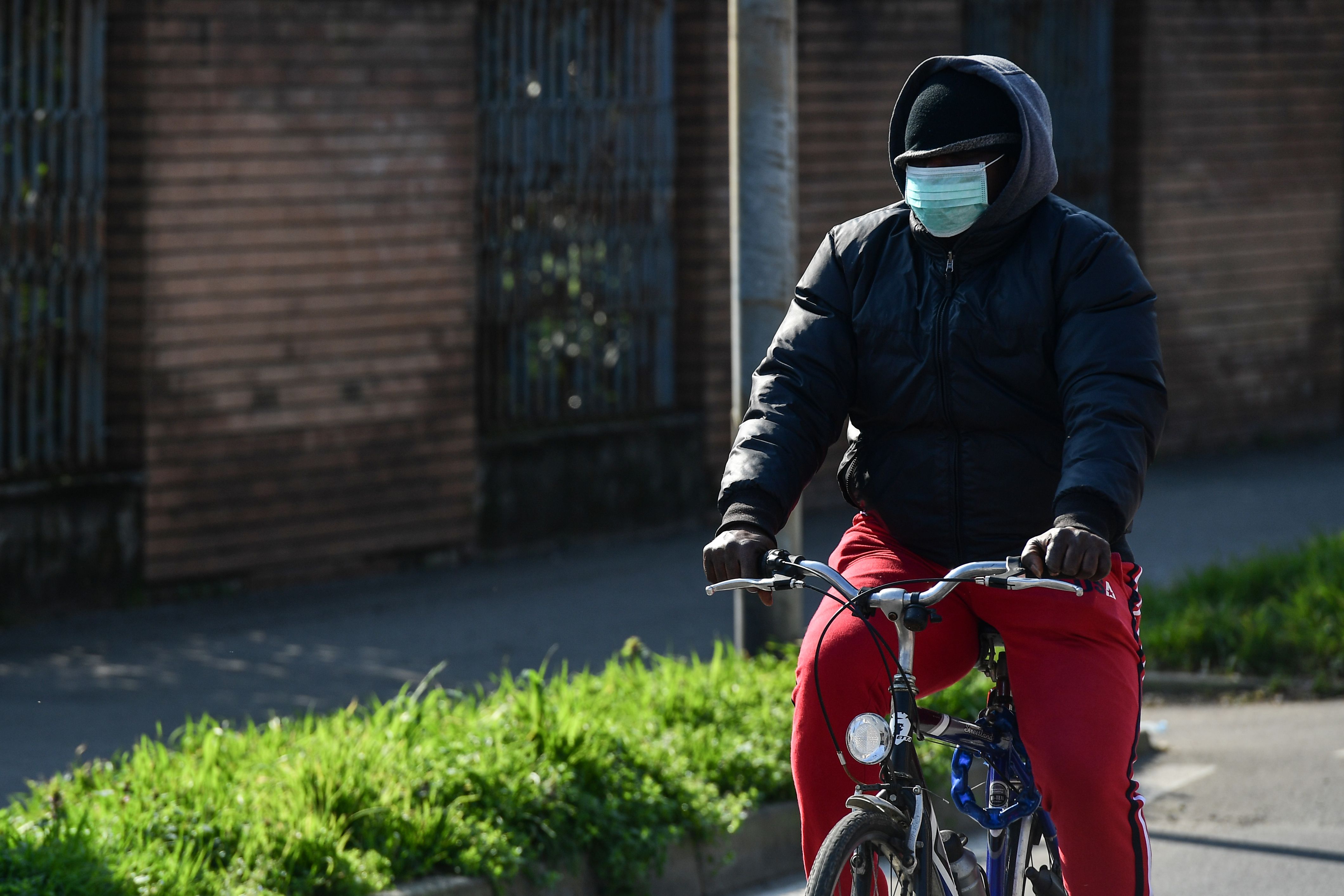 Warga Milan, Italia, bersepeda sembari menggunakan masker