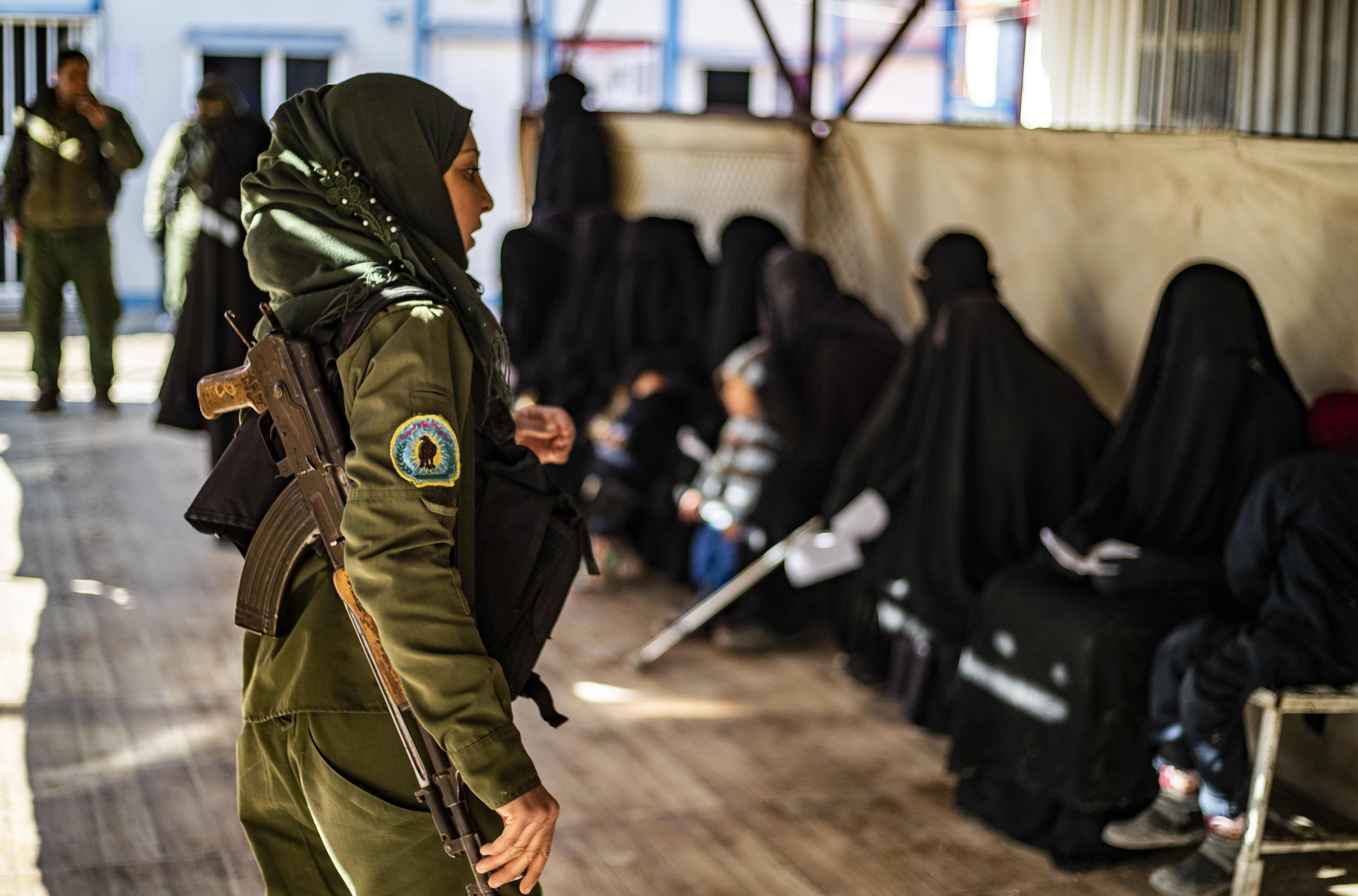 Milisi Kurdi mengawasi wanita anggota keluarga eks kombatan IS di kamp pengungsian di Timur Laut Suriah