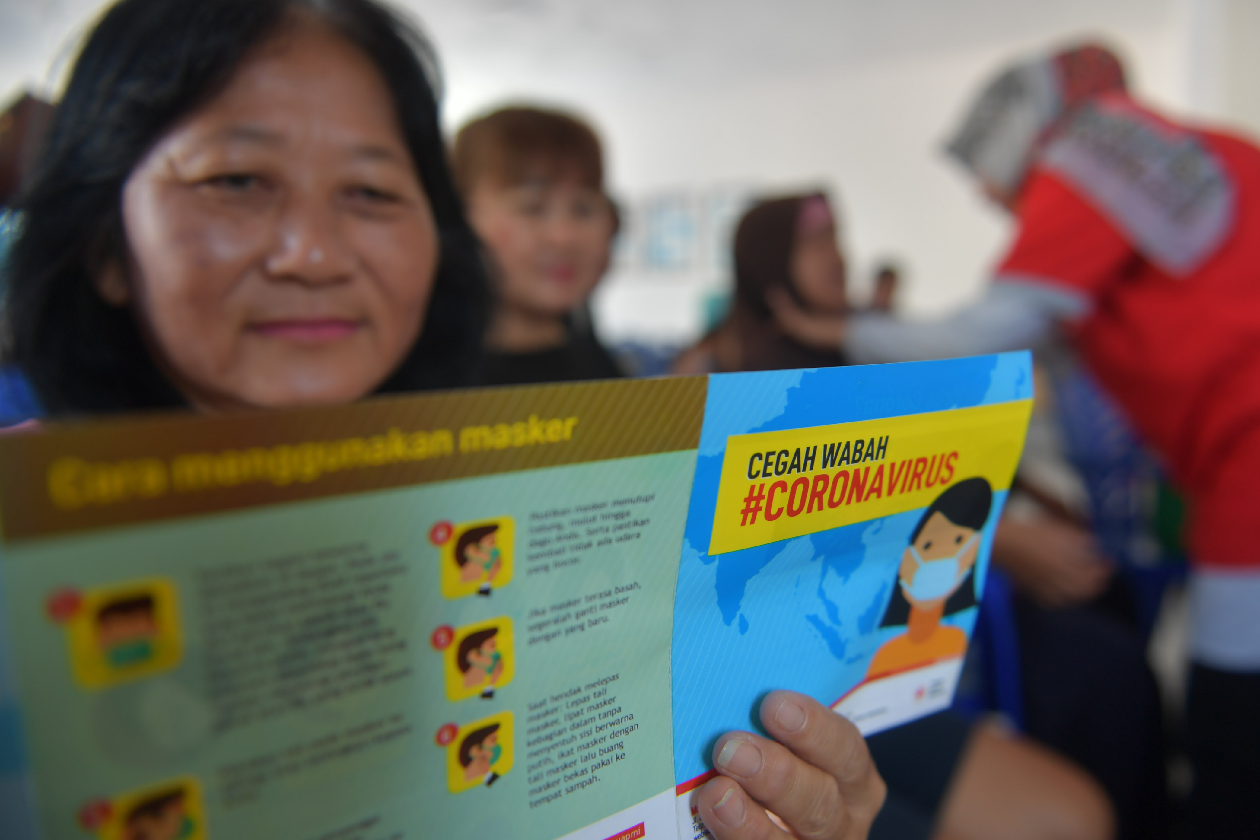 Seorang warga membaca pamflet sosialisasi pencegahan virus Corona yang dibagikan oleh Palang Merah Indonesia (PMI)