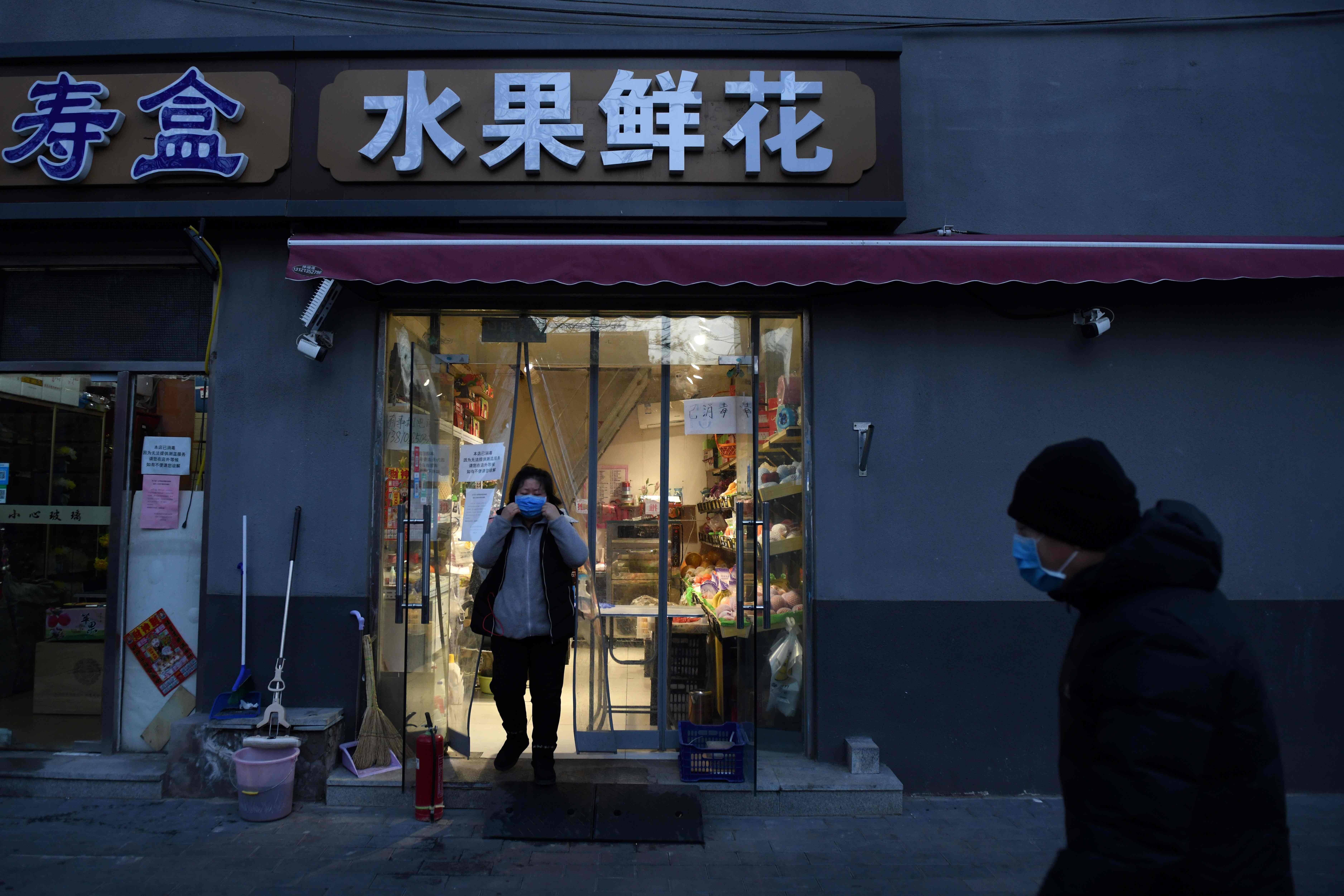Seorang penjual memakai masker wajah sebagai pencegahan coronavirus COVID-19 ketika ia berdiri di toko buahnya di Beijing, Jumat (21/2). 
