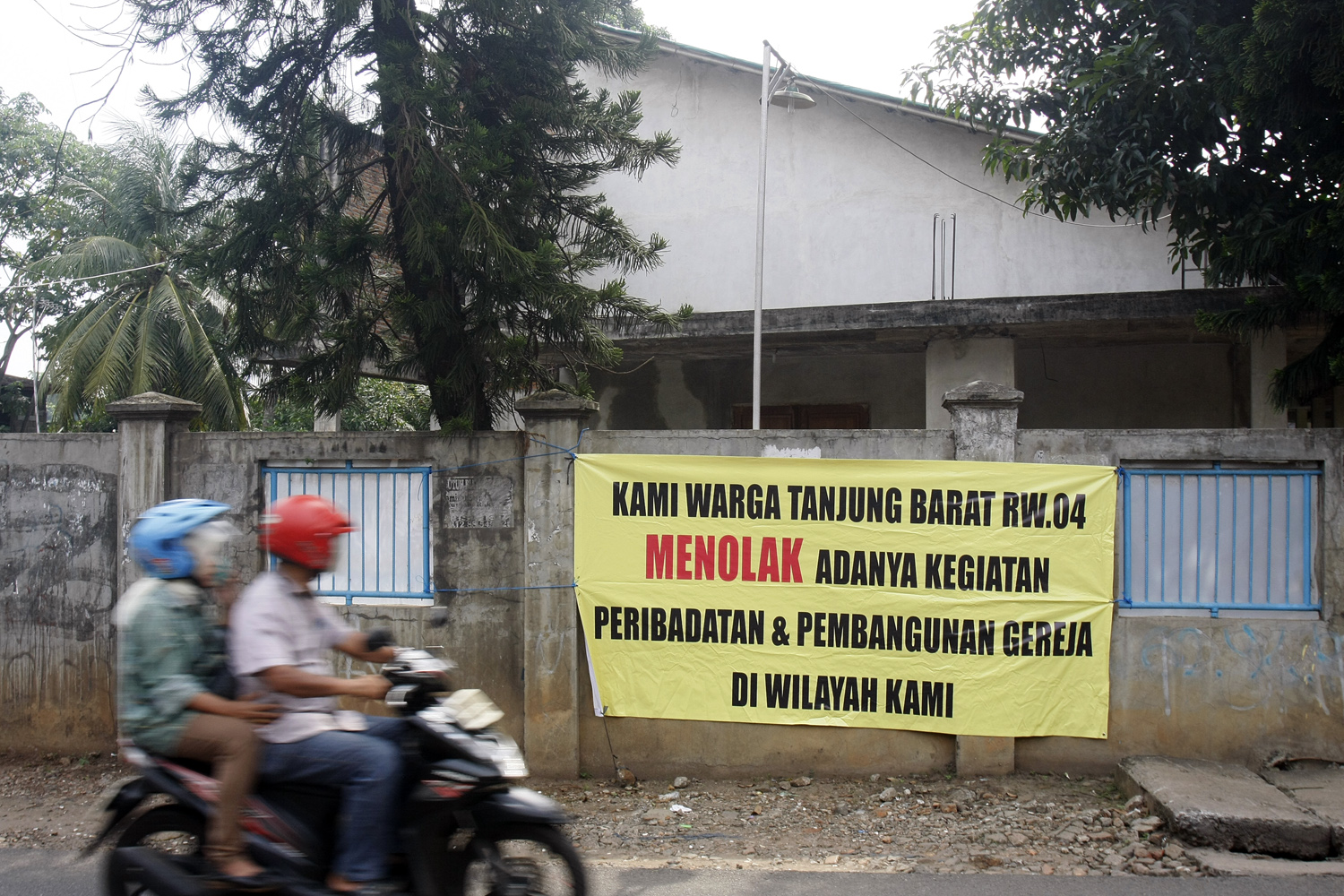 Warga melintas di dekat spanduk penolakan adanya kegiatan peribadatan sekaligus pembangunan gereja di Jalan Tanjung Barat Lama, Jagakarsa.