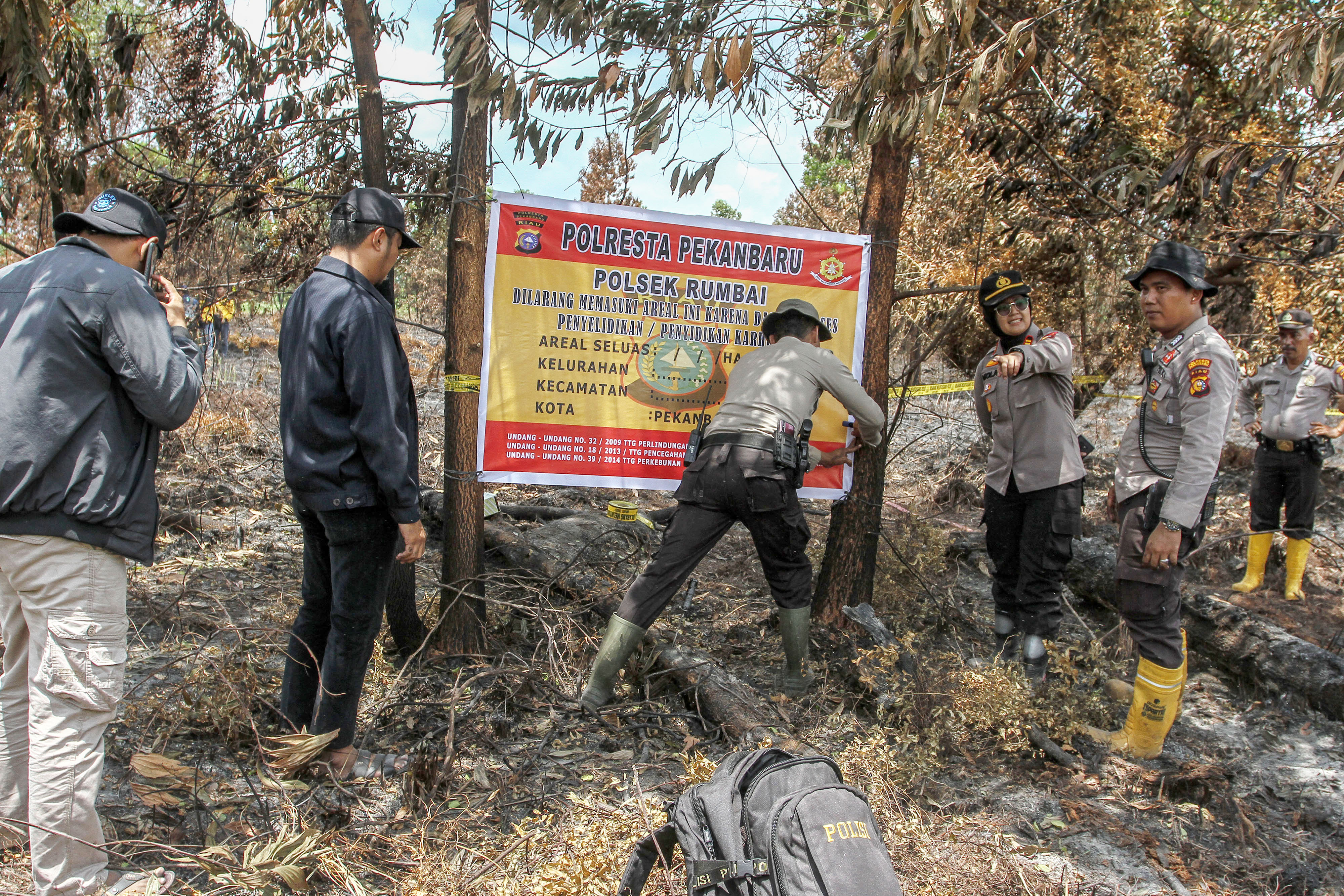 Anggota Polri memasang garis polisi usai melakukan pemadaman di lokasi kebakaran lahan di Pekanbaru, Riau, Kamis (27/2).
