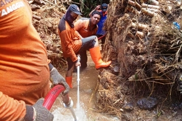 Para petugas sedang membersihkan saluran irigasi yang tersumbat.