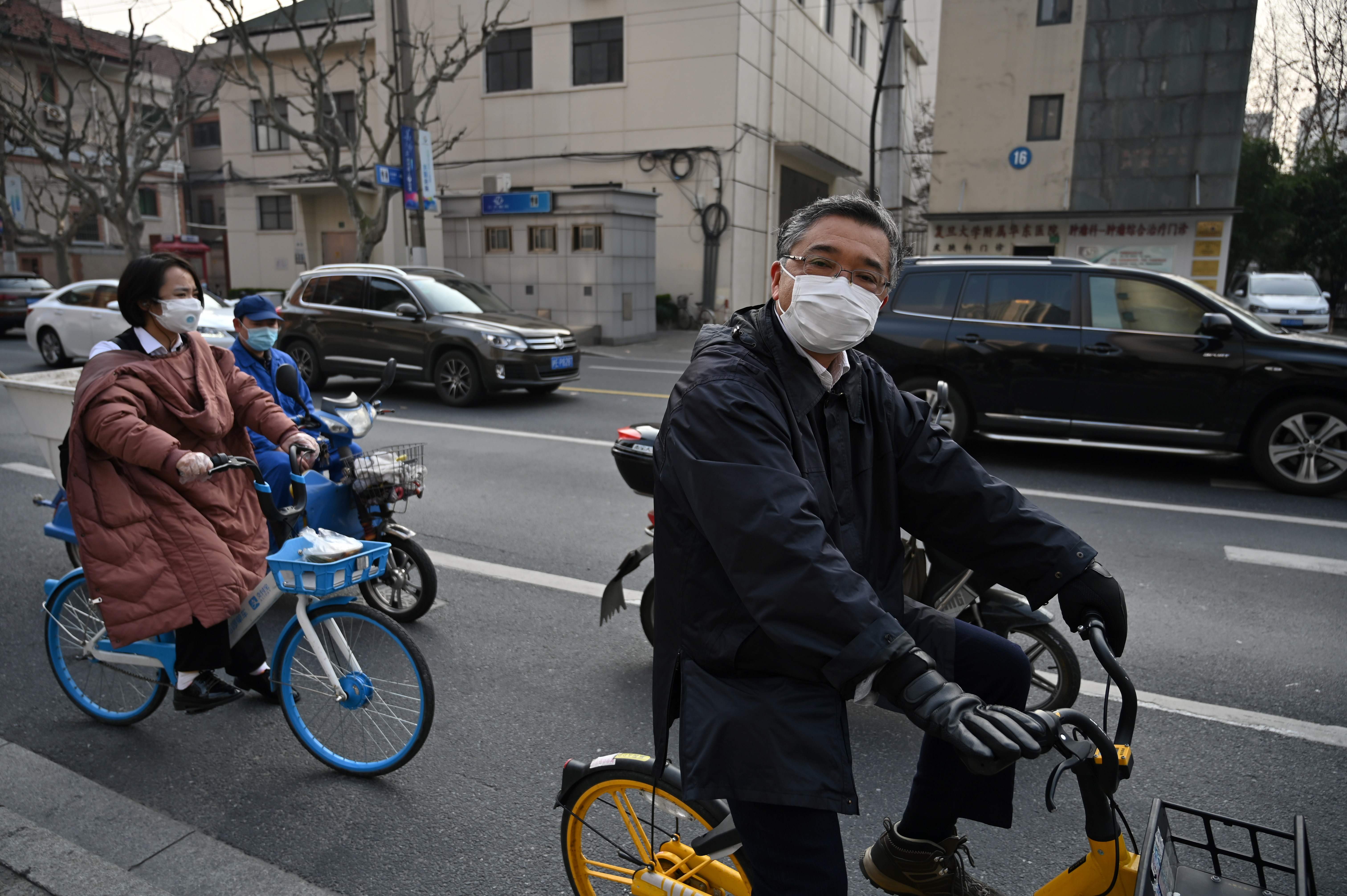 Warga Tiongkok yang menggunakan masker bersepeda di Shanghai, Tiongkok. Sejumlah provinsi kecuali di Hubei, aktivitas warga mulai tampak.