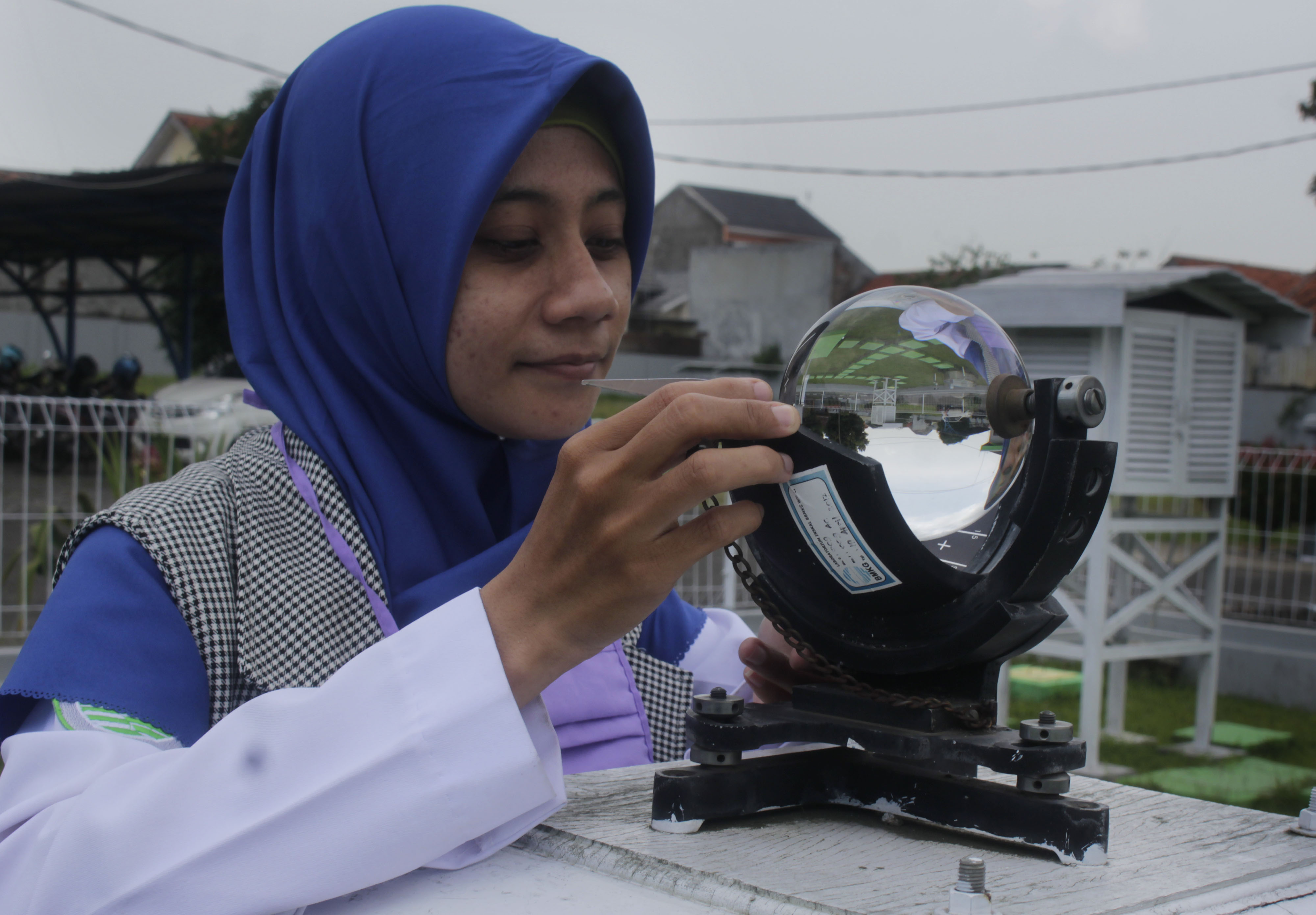 Seorang petugas BMKG tengah mengamati cuaca menggunakan alat 