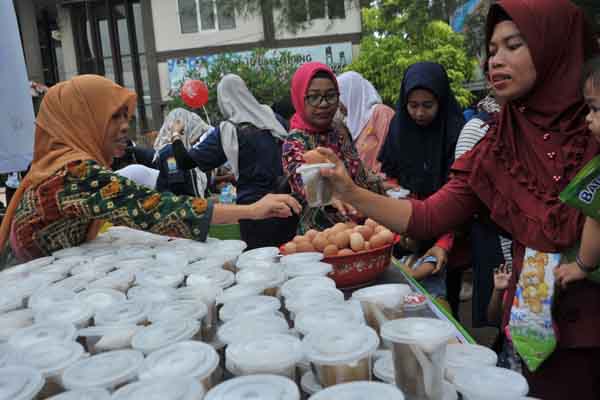 Ilustrasi : Petugas dan kader Posyandu membagikan bubur kacang hijau dan telur rebus dalam rangka Hari Gizi Nasional.