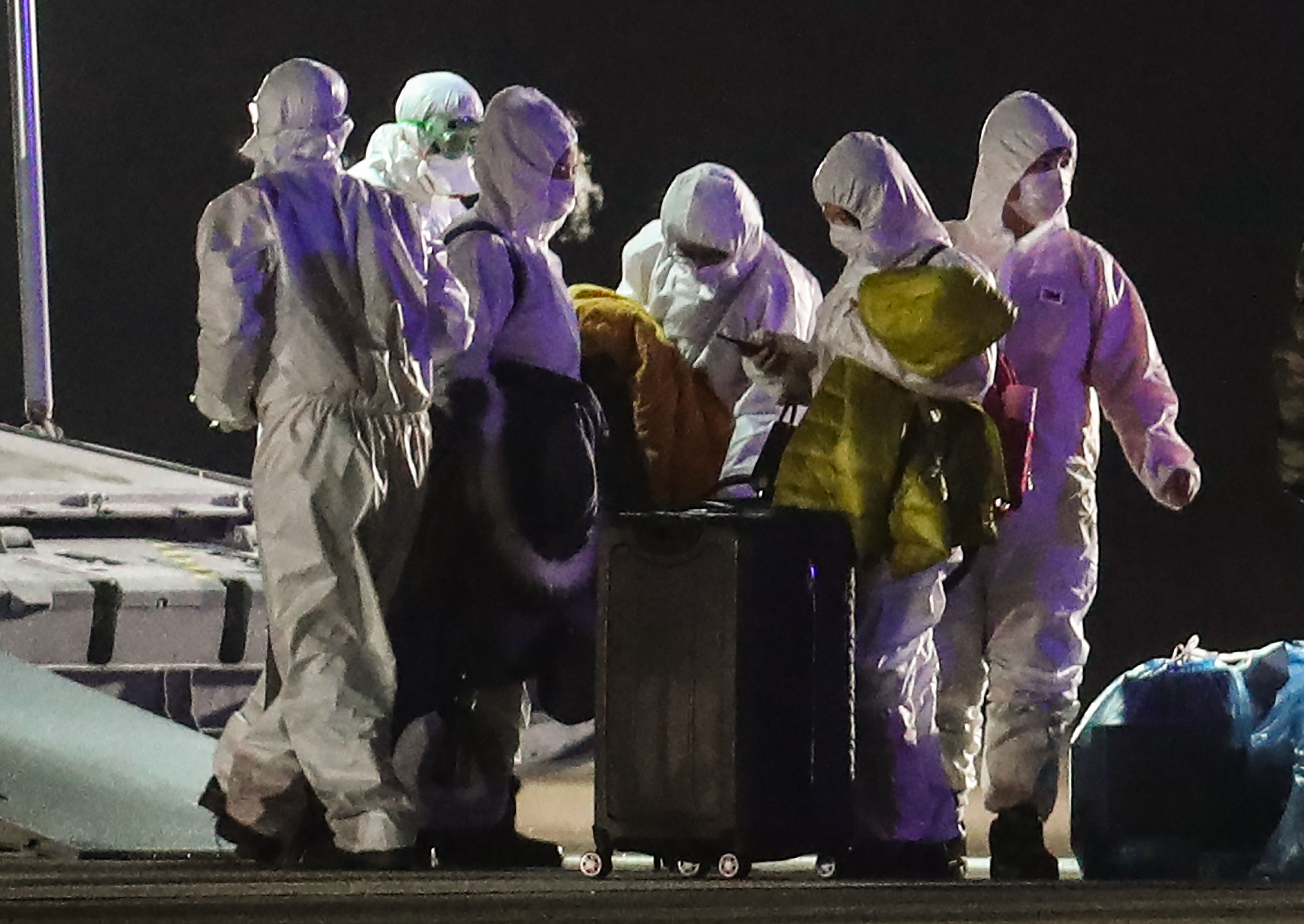 Petugas berbaju khusus mengevakuasi para penumpang WN Turki yang tiba di bandara militer Turki, di Ankara dari Wuhan, 1 Februari 2020.
