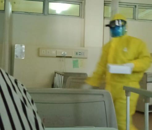 Pasien di kamar isolasi memotret petugas medis dengan mengenakan APD  membawakan sarapan. 