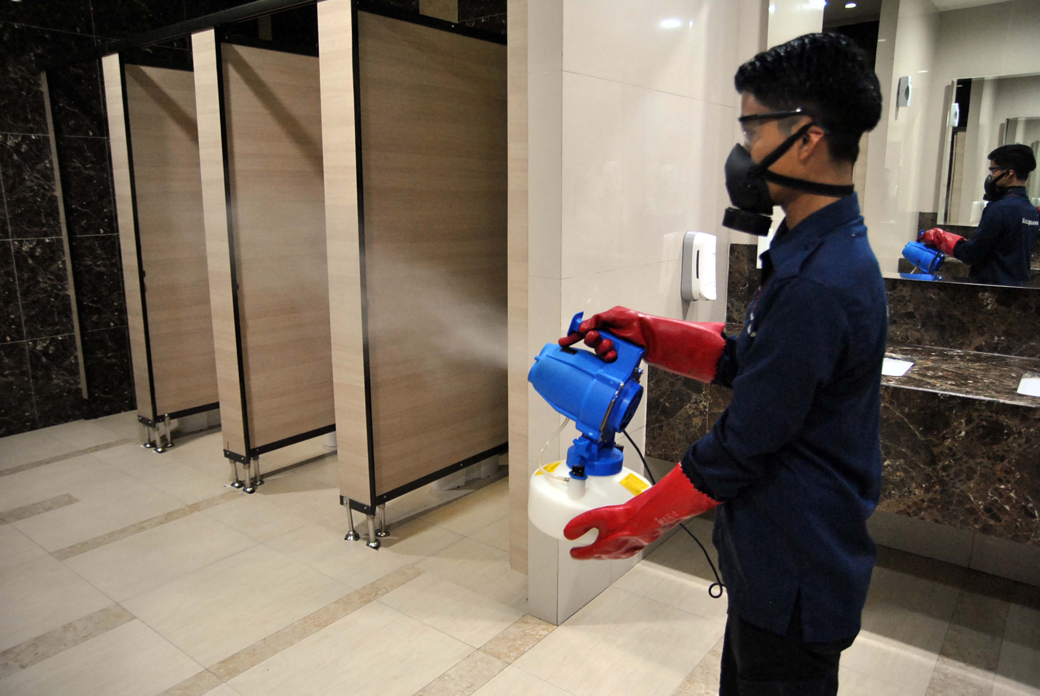 Pekerja menyemprotkan cairan disinfektan ke dalam toilet di pusat perbelanjaan Ciibinong City Mall, Kabupaten Bogor, Jawa Barat, Sabtu