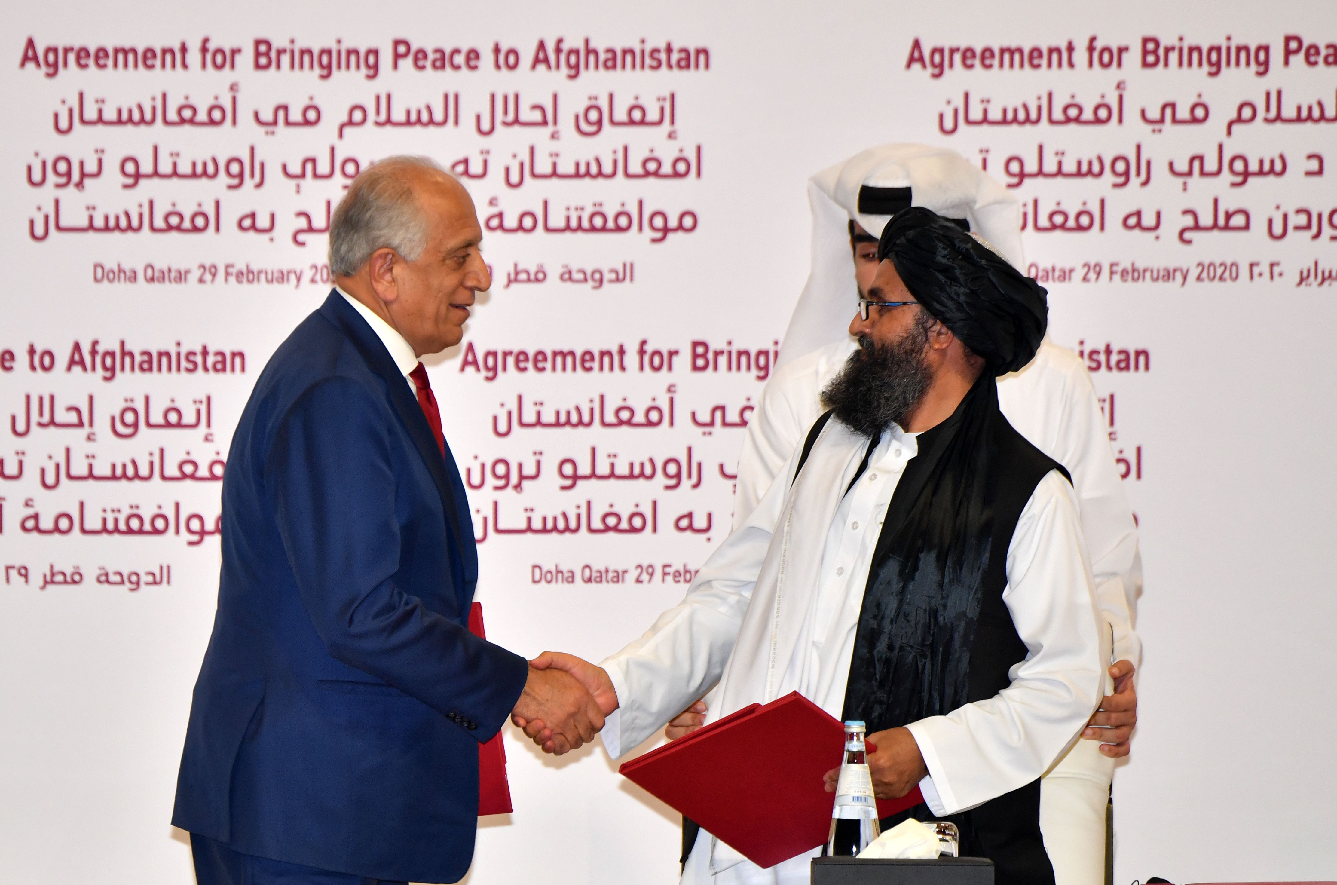 Perwakilan Khusus AS untuk Rekonsiliasi Afghansistan Zalmay Khalilzad dan pendiri Taliban Abdul Ghani Baradar berjabat tangan di Qatar.