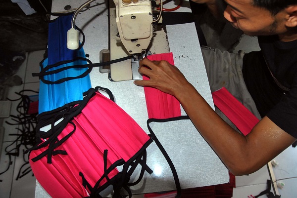 Ilustrasi Penjahit mengerjakan pembuatan masker dari bahan kain katun 