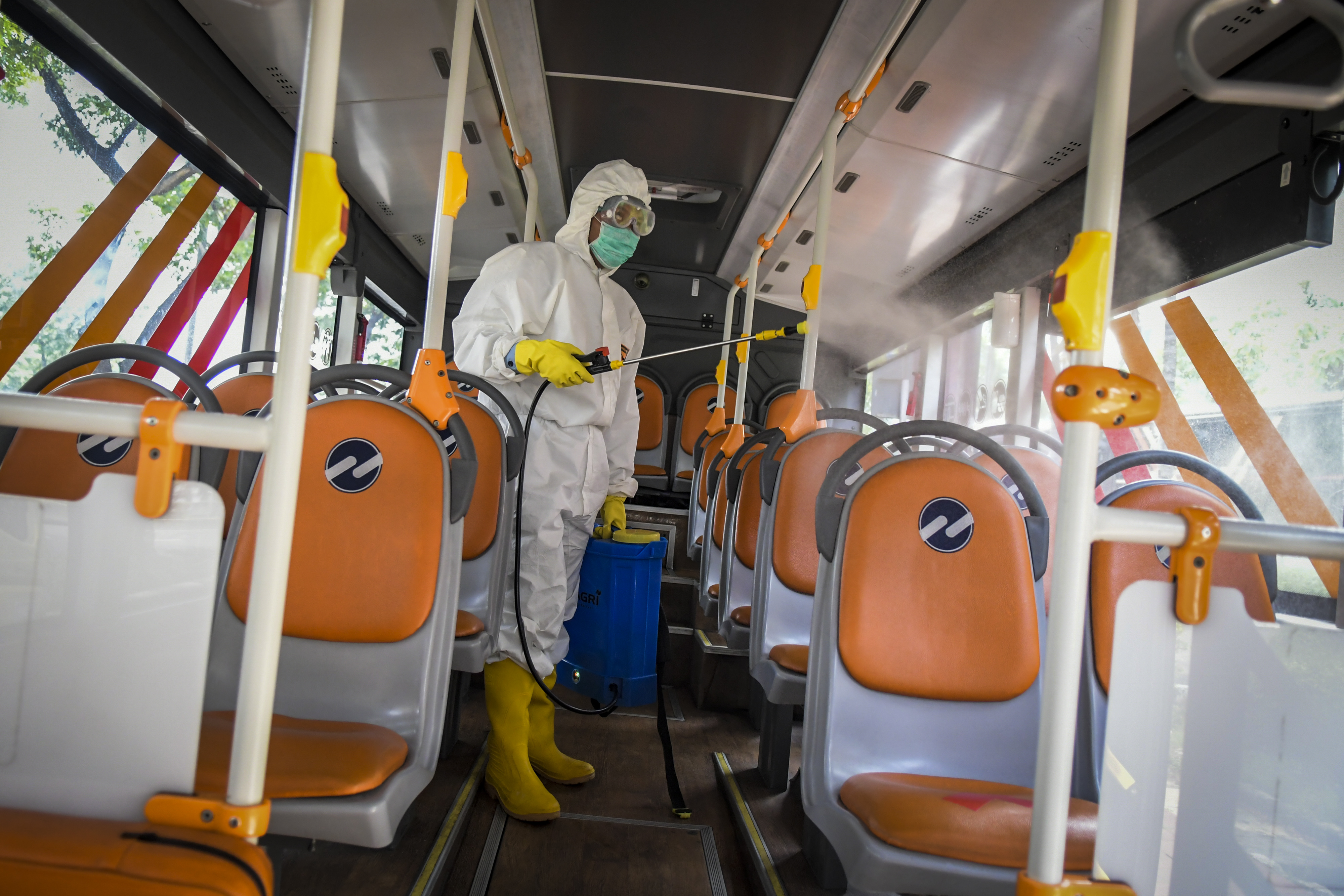 Petugas menyemprotkan cairan disinfektan di bus Transjakarta.