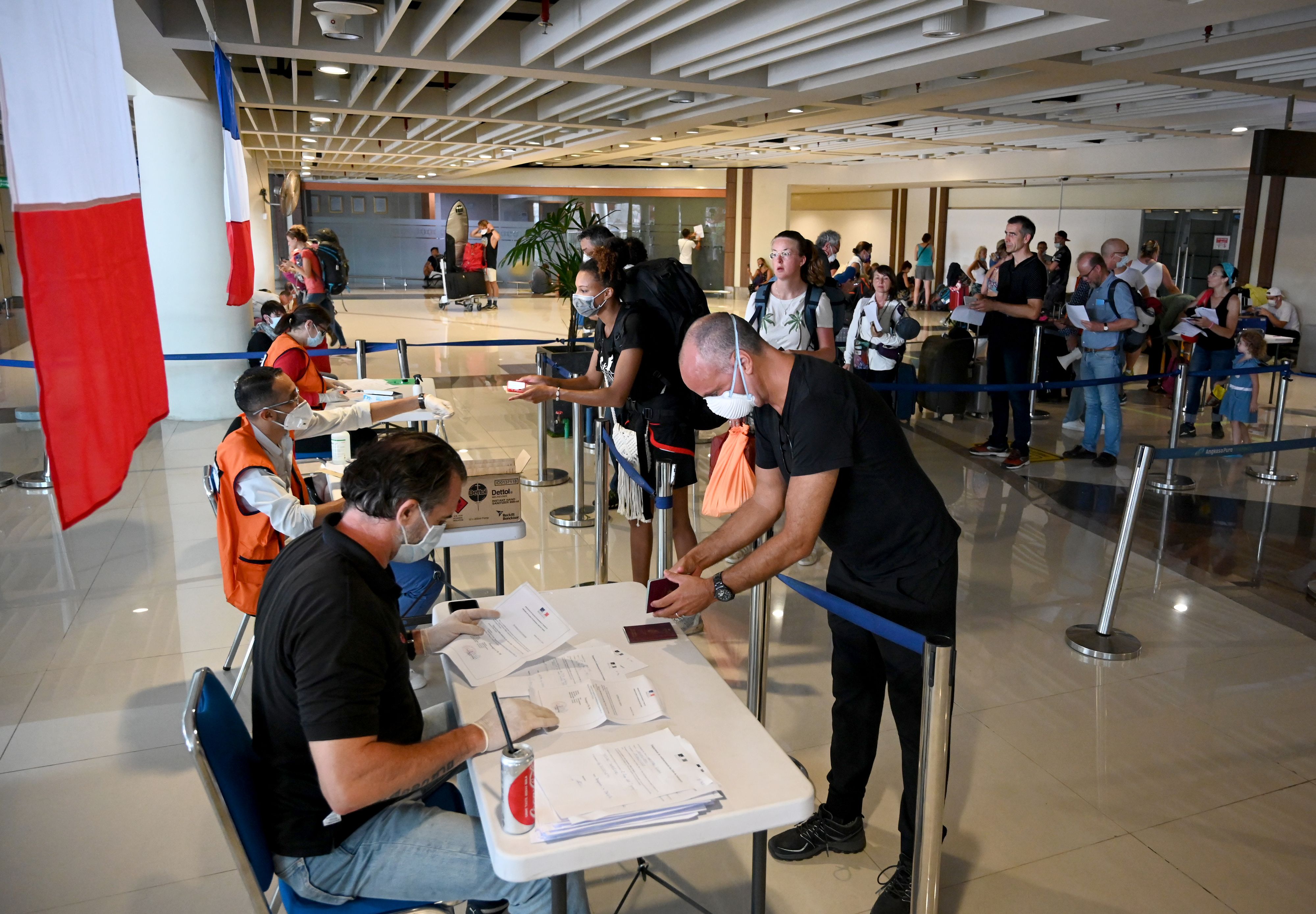 Para turis sedang antre di depan petugas Kedutaan Perancis untuk dievakuasi di Bandara Ngurah Rai pada 28 Maret