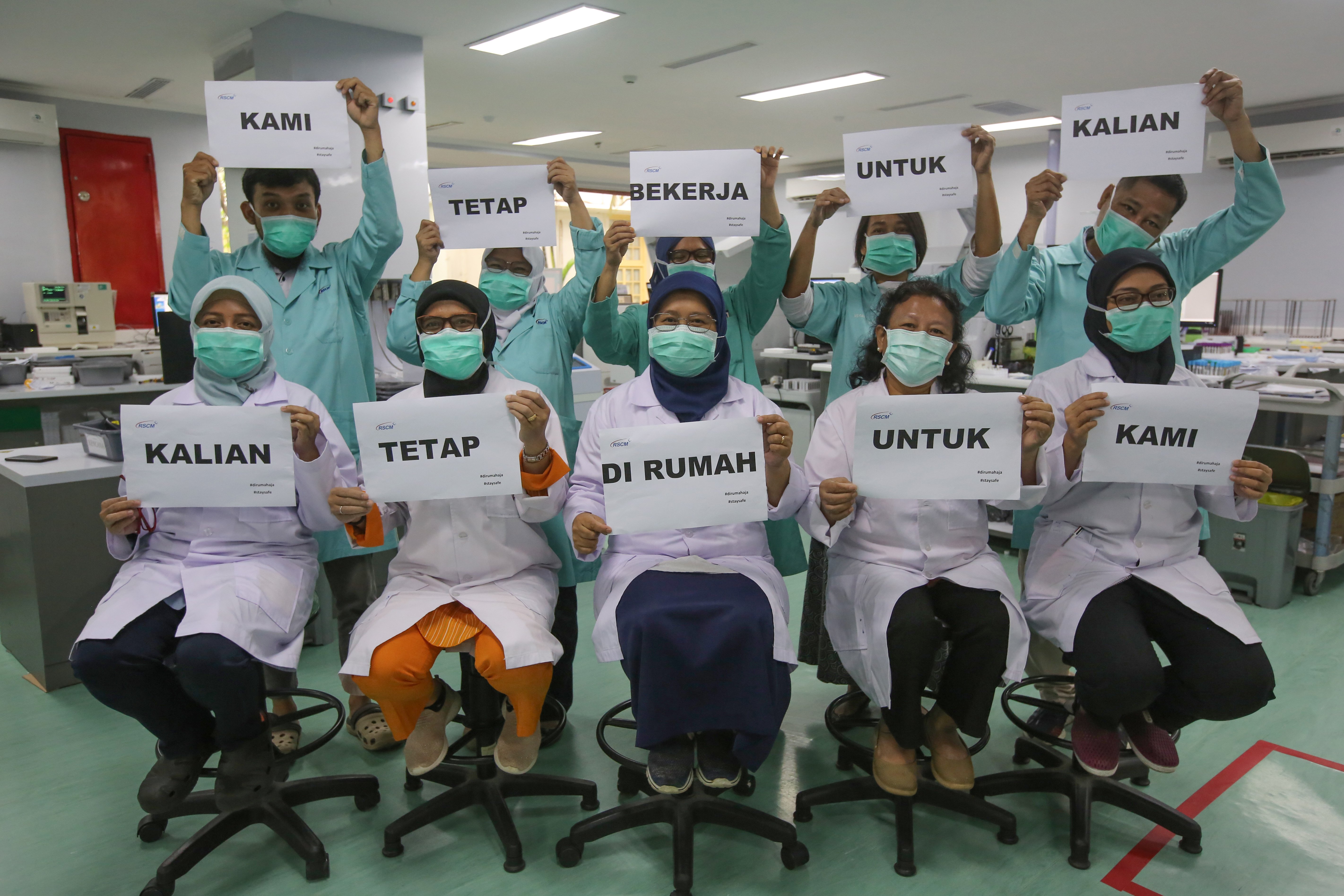 Petugas medis melakukan foto dengan memegang tulisan 