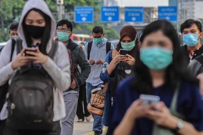 Pekerja menggunakan masker pelindung saat melewati trotoar menuju kantornya di kawasan Sudirman, Jakarta, Selasa, 3 Maret 2020