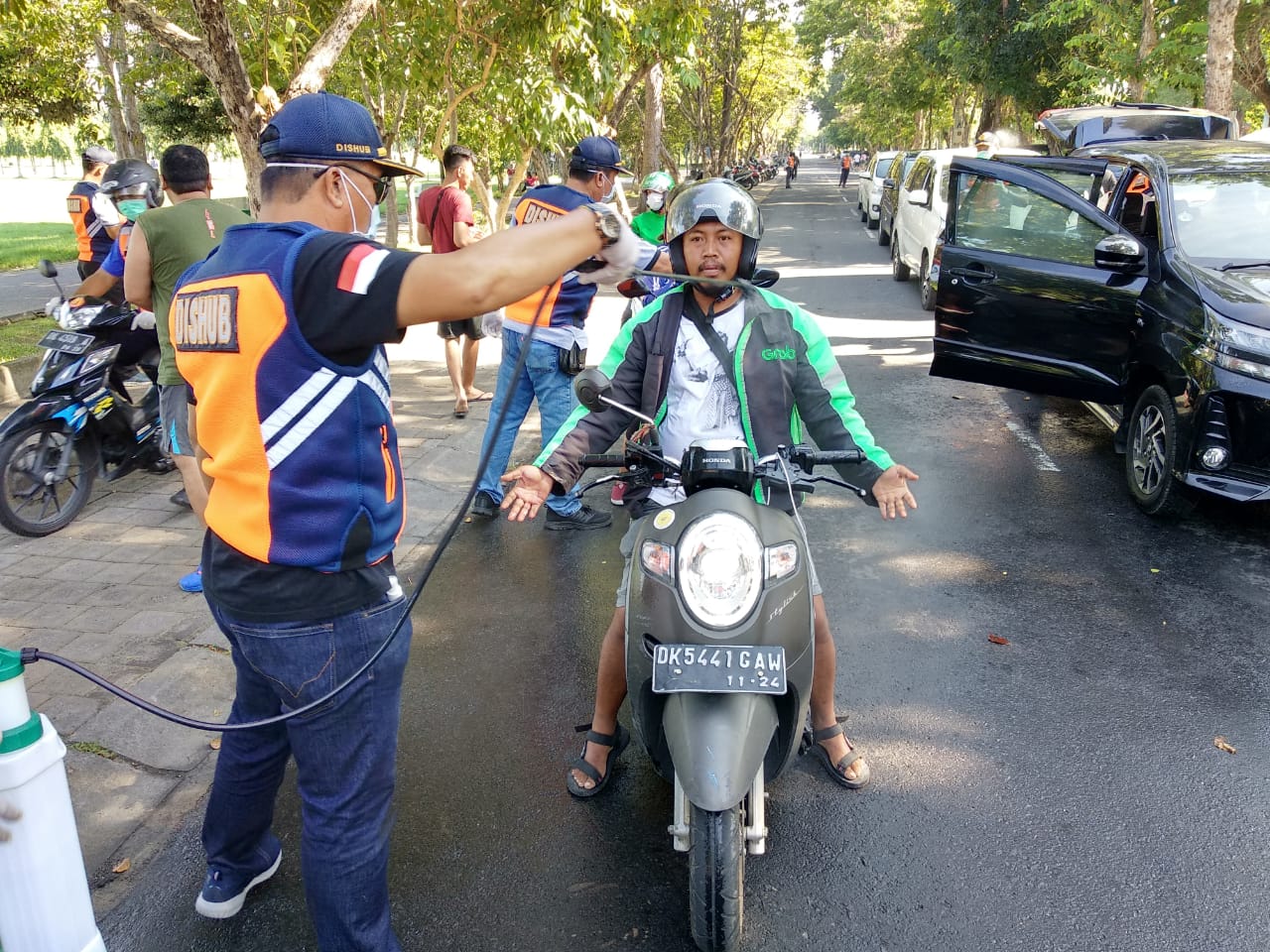 Petugas dari Dinkes Kota Denpasar dan Dinas Perhubungan melakukan semprot badan terhadap pengemudi Ojol di beberapa titik Kota Denpasar 