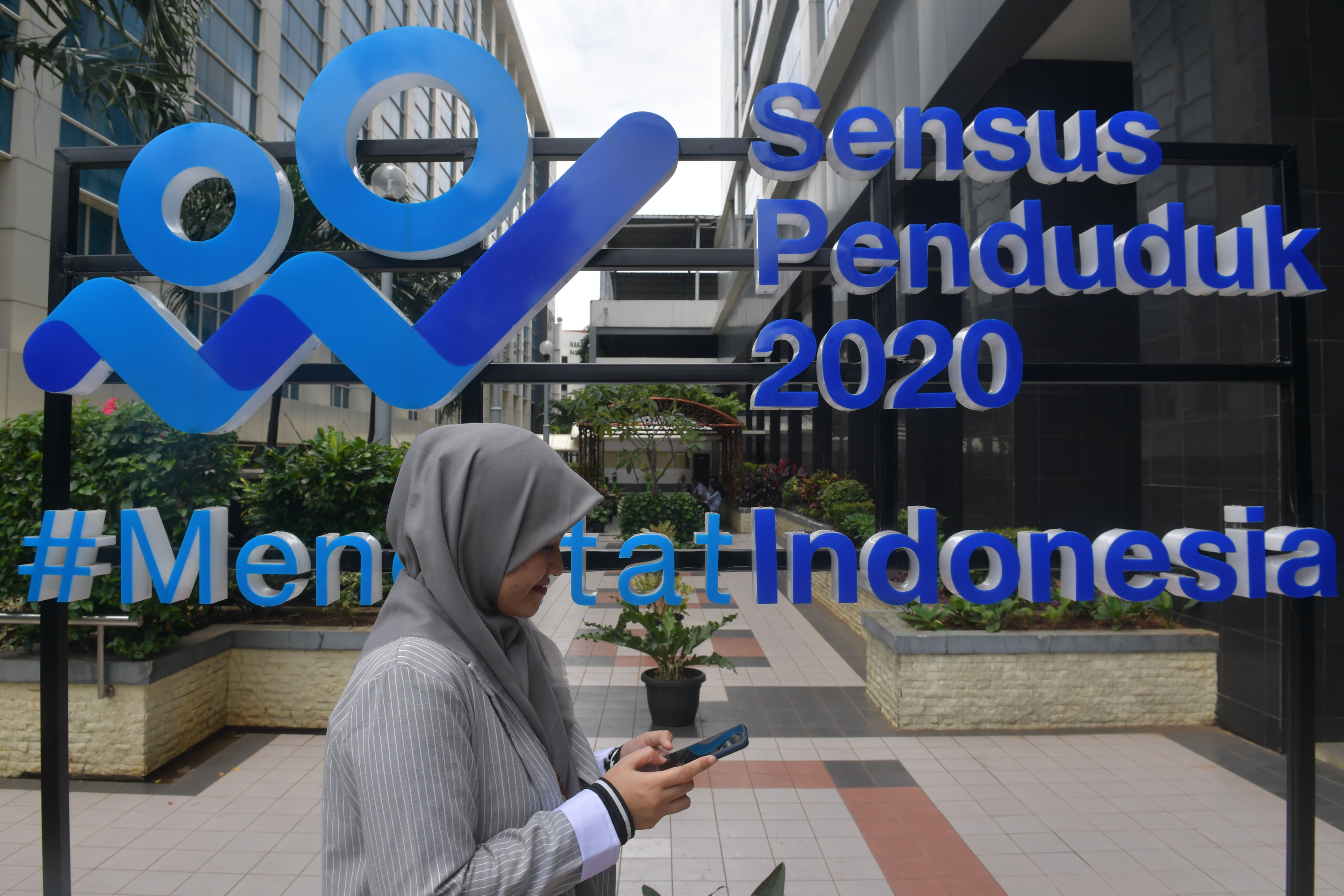 Seorang perempuan melintas di depan tulisan 