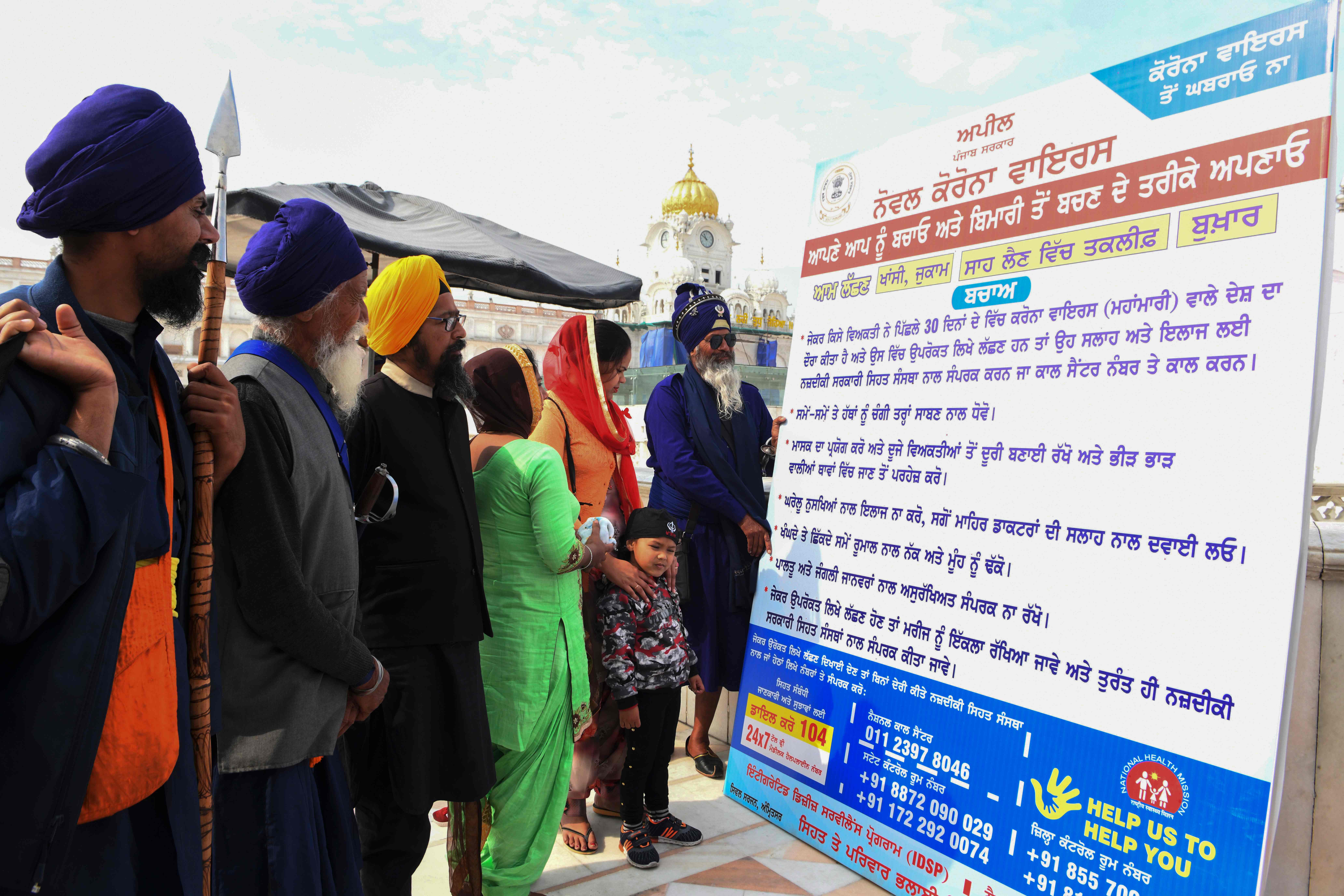 Warga penganut Sikh membaca papan informasi mengenai cara pencegahan infeksi virus korona di Amritsar, India.