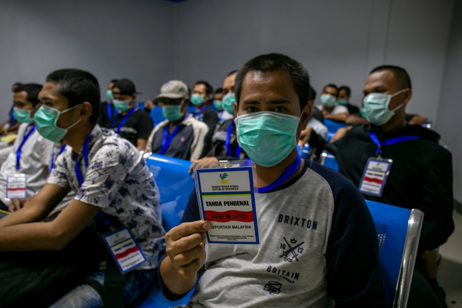 Pekerja migran Indonesia menunjukkan tanda pengenal deportasi ketika dilakukan pendataan kesehatan oleh petugas KKP di Pelabuhan Batam.
