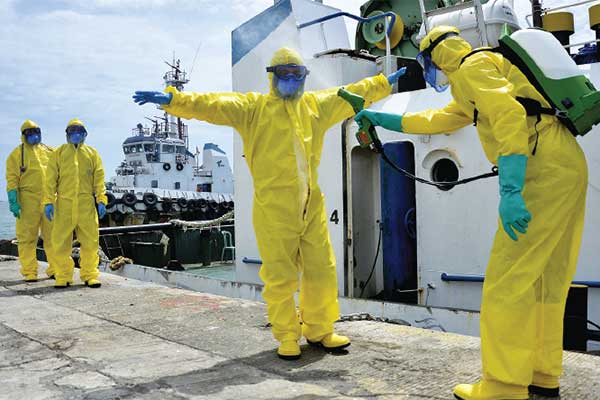 Simulasi -- Tim medis menyemprotkan disinfektan pada rekannya seusai mengevakuasi WNA terjangkit virus korona (covid-19) turun dari kapal