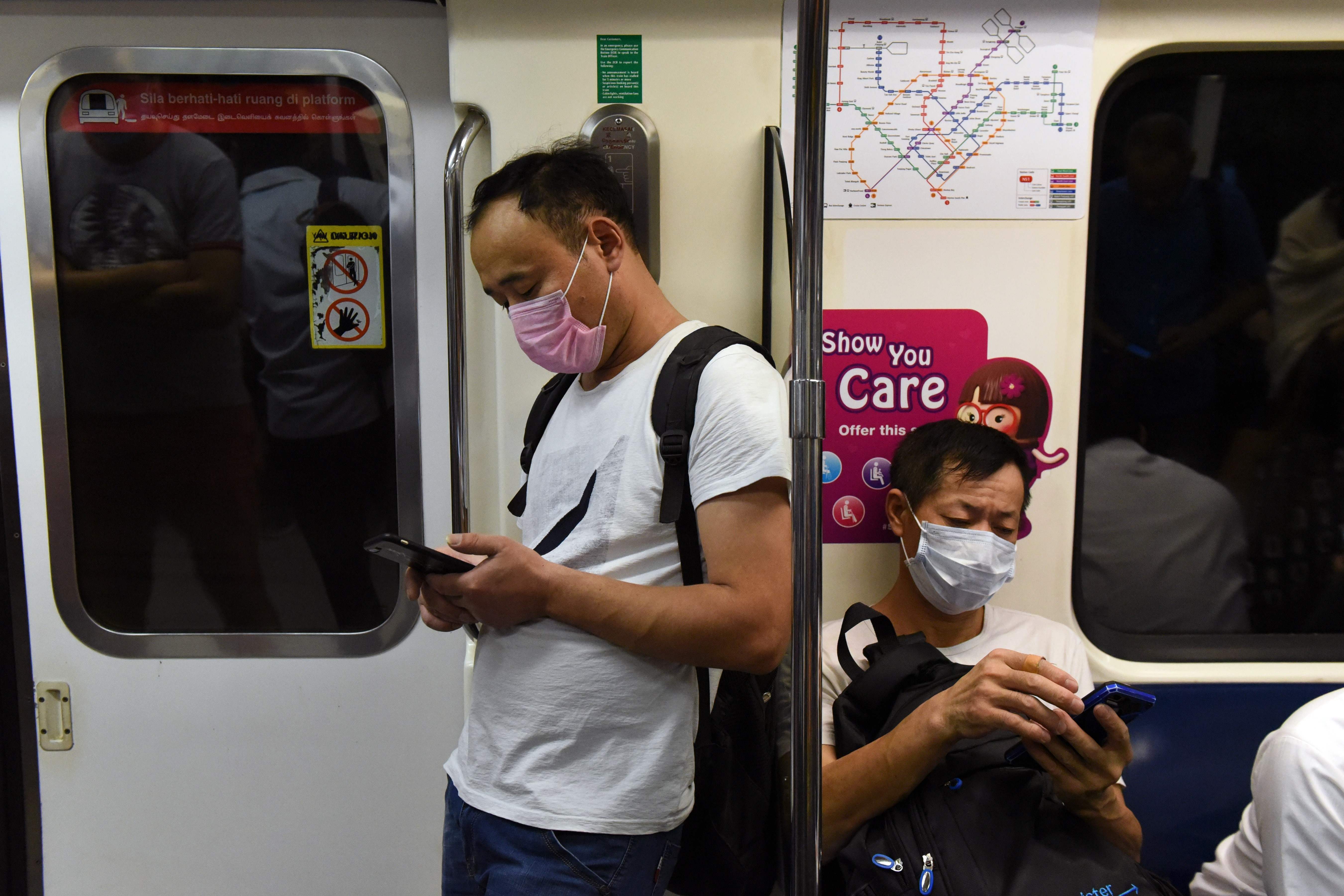 Warga mengenakan masker saat menumpang MRT di Singapura