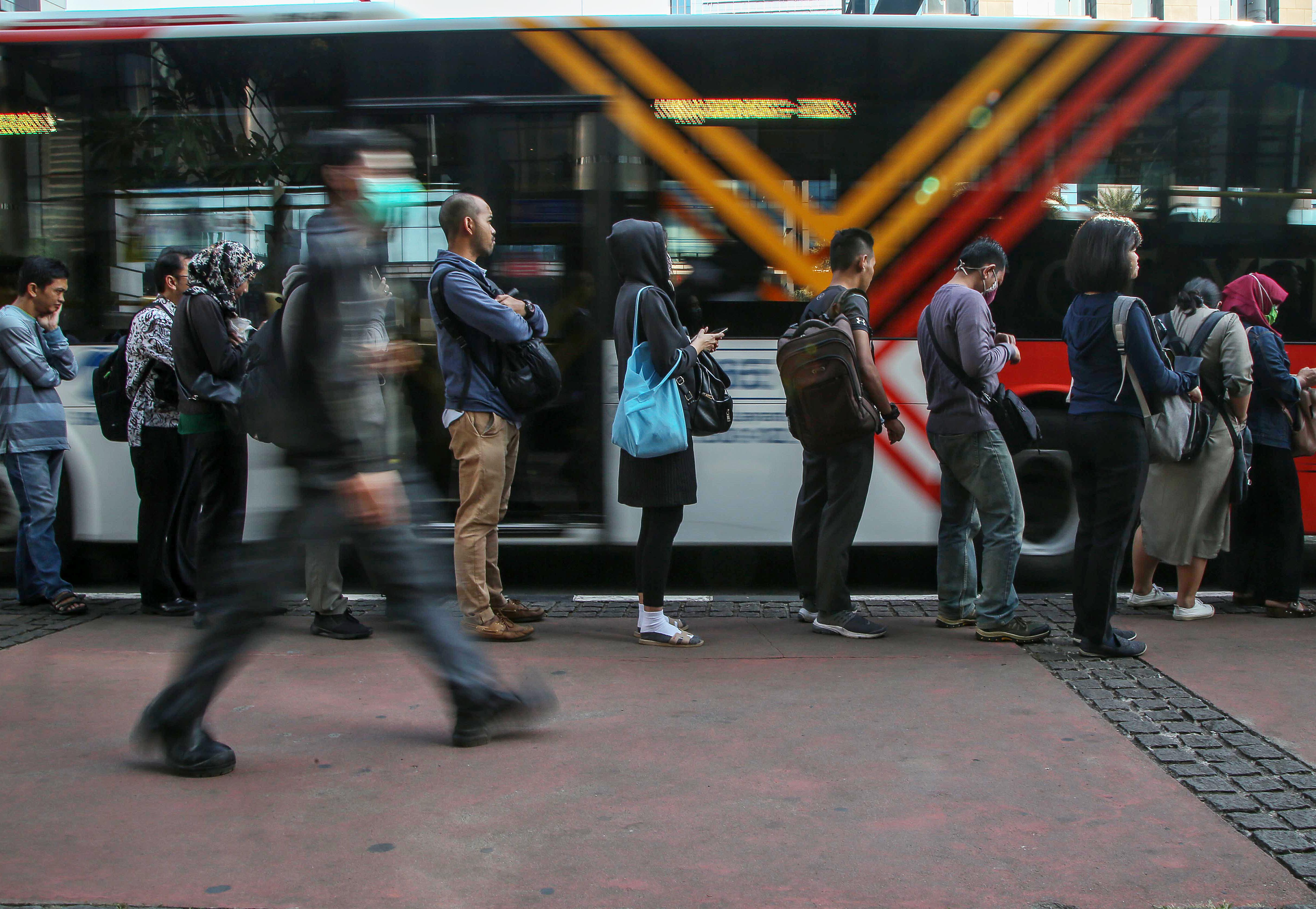 Penumpang berbaris menaiki armada low entry bus TransJakarta