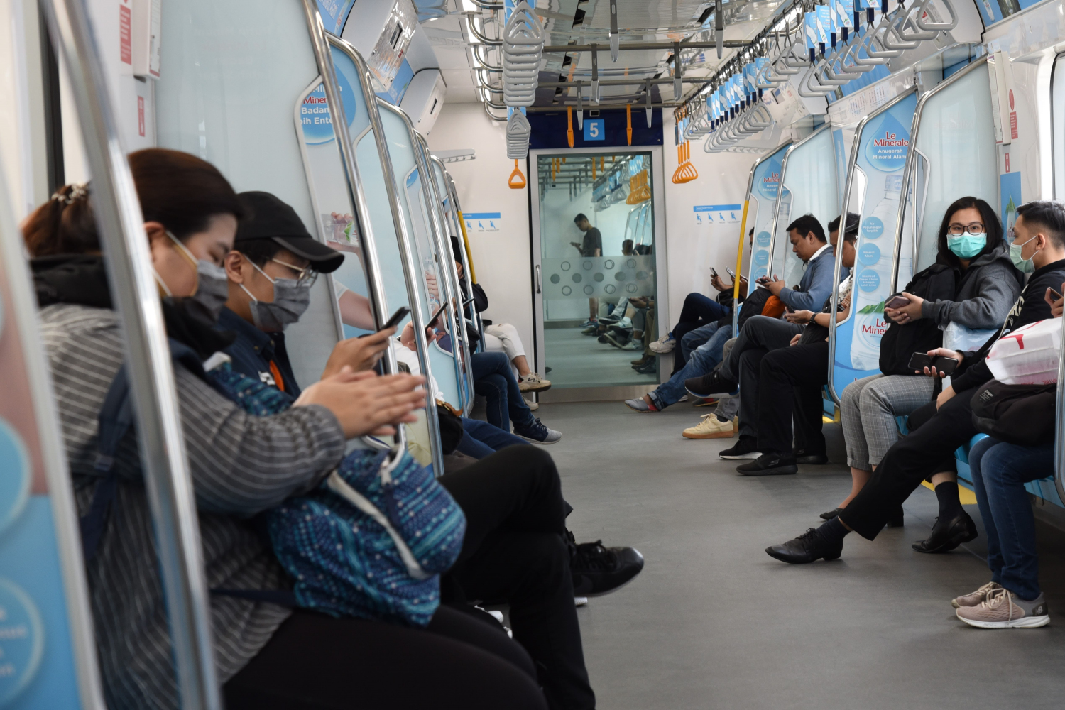Penumpang menggunakan masker saat berada di dalam Moda Raya Terpadu (MRT), untuk menghindari penyebaran virus korona.