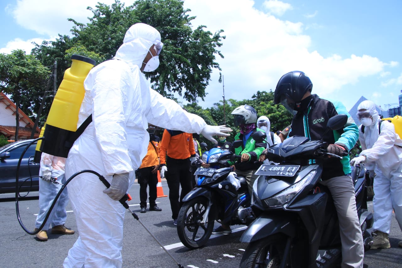Proses penyemprotan disinfektan pengendara ojek online di Jatim.