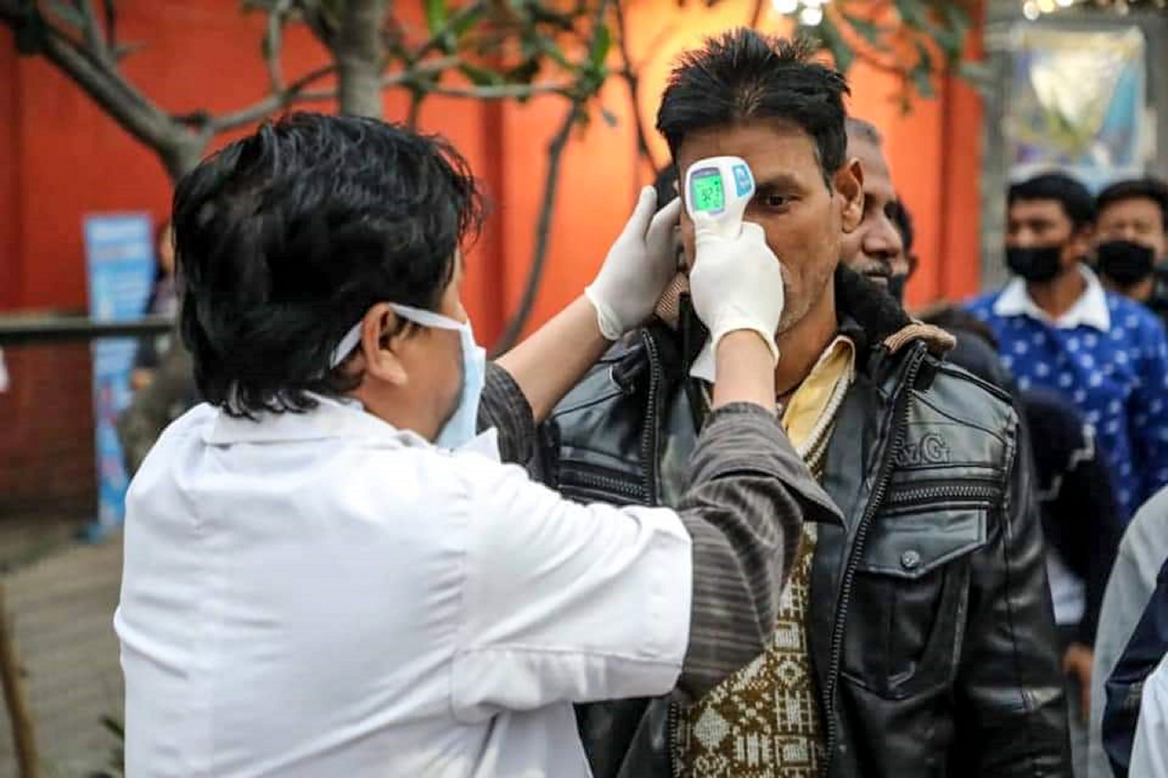 Seorang petugas kesehatan memeriksa suhu tubuh pengunjung di perbatasan antara Bhutan dan India.