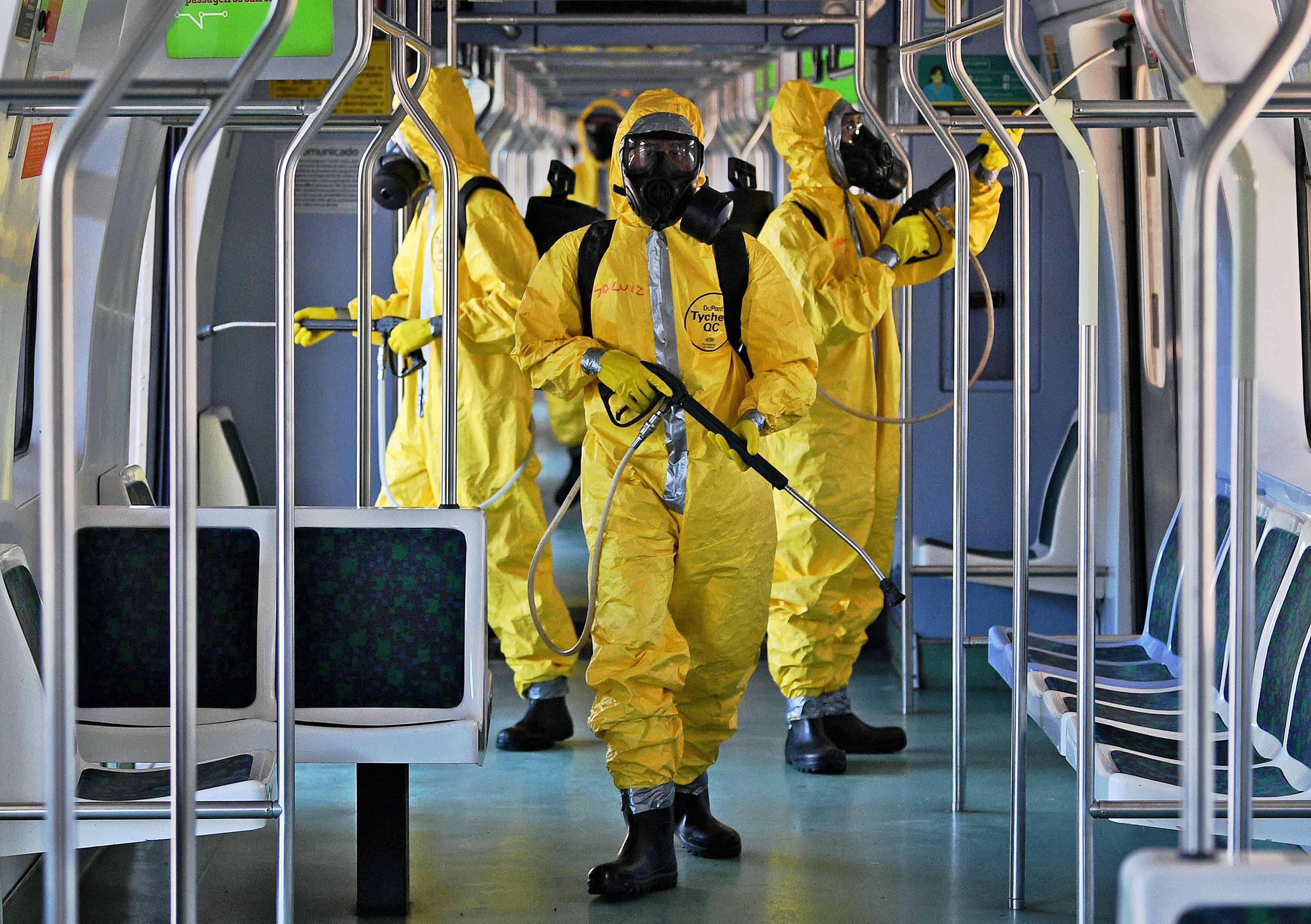 Personel militer Brasil mengenakan APD menyemprotkan disinfektan di gerbong kereta di Rio de Janeiro.