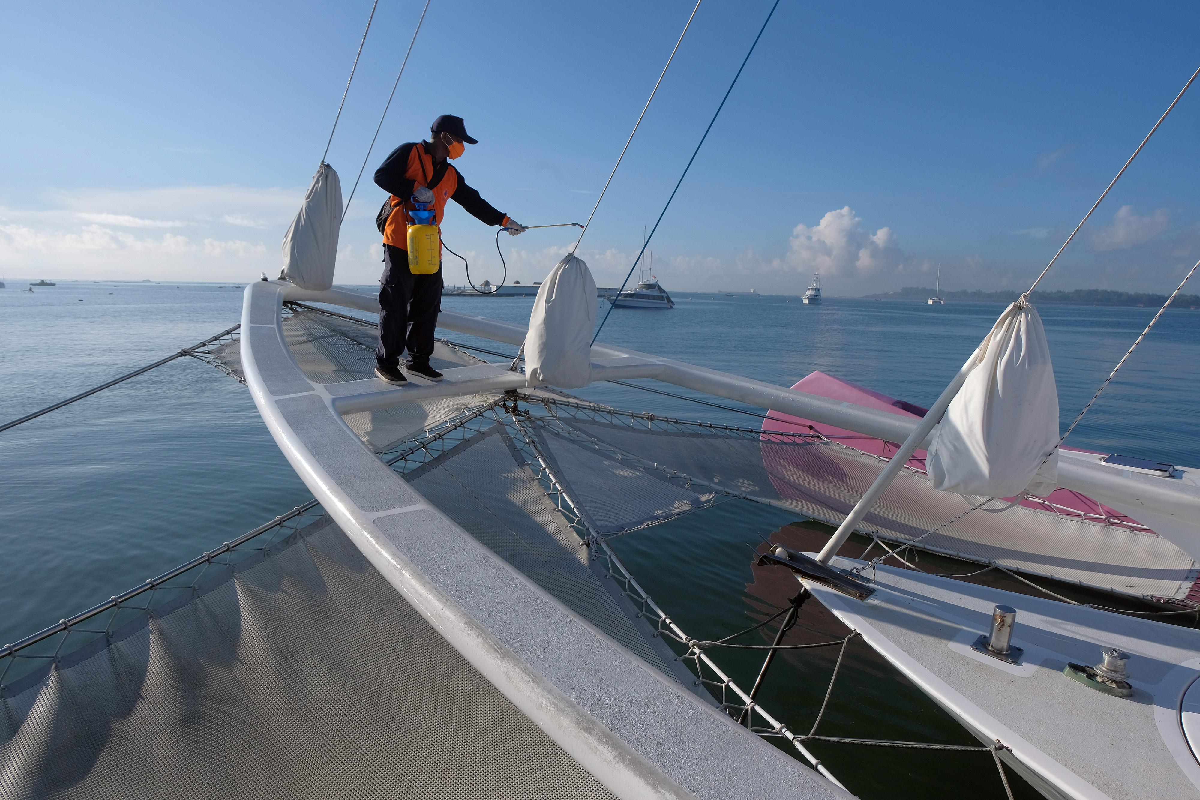 Petugas menyemprotkan disinfektan pada kapal wisata di Pantai Mertasari, Sanur, Denpasar, Bali, Minggu (15/3).