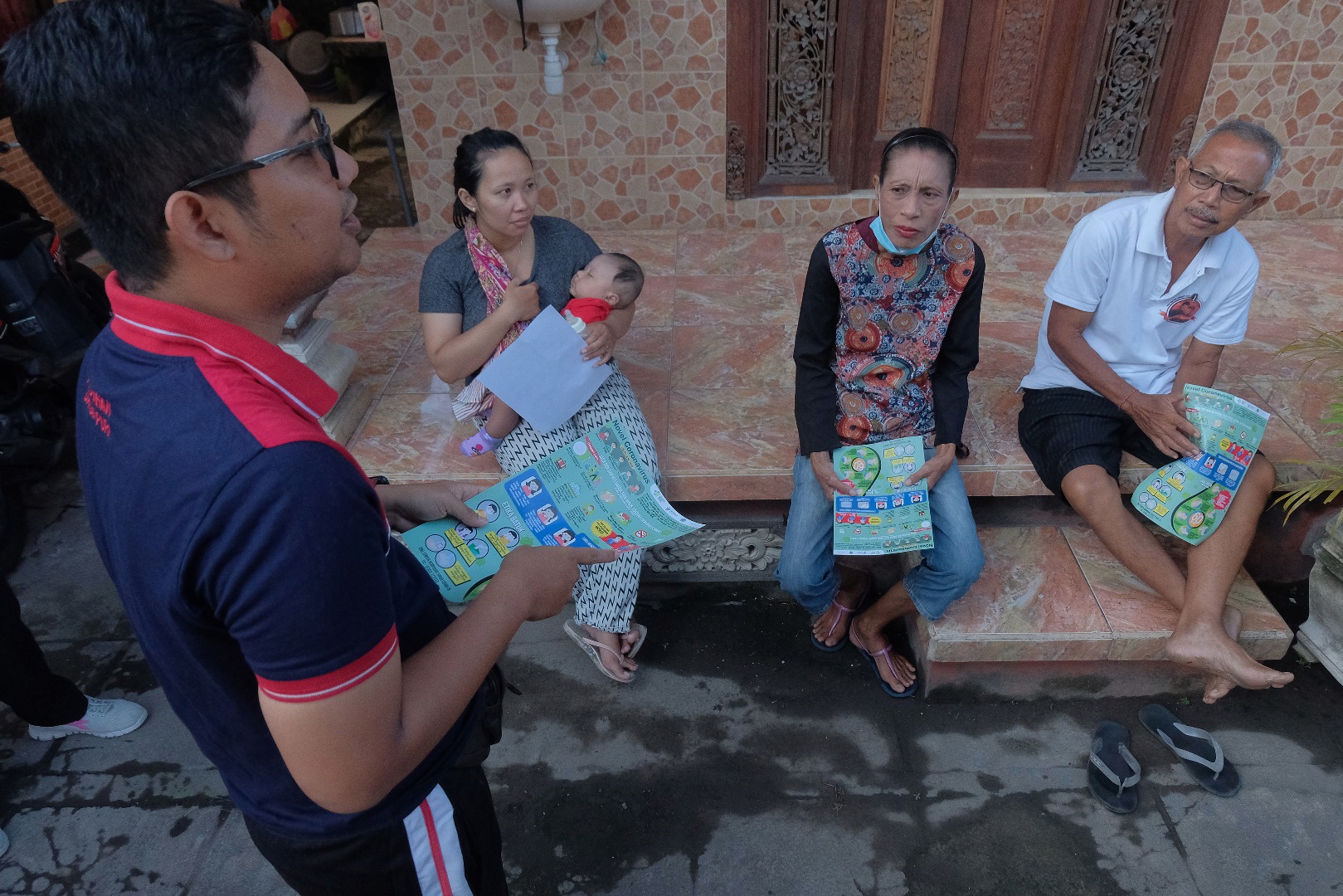 Aparatur desa menjelaskan cara penanggulangan COVID-19 saat sosialisasi ke rumah warga di Denpasar, Bali.