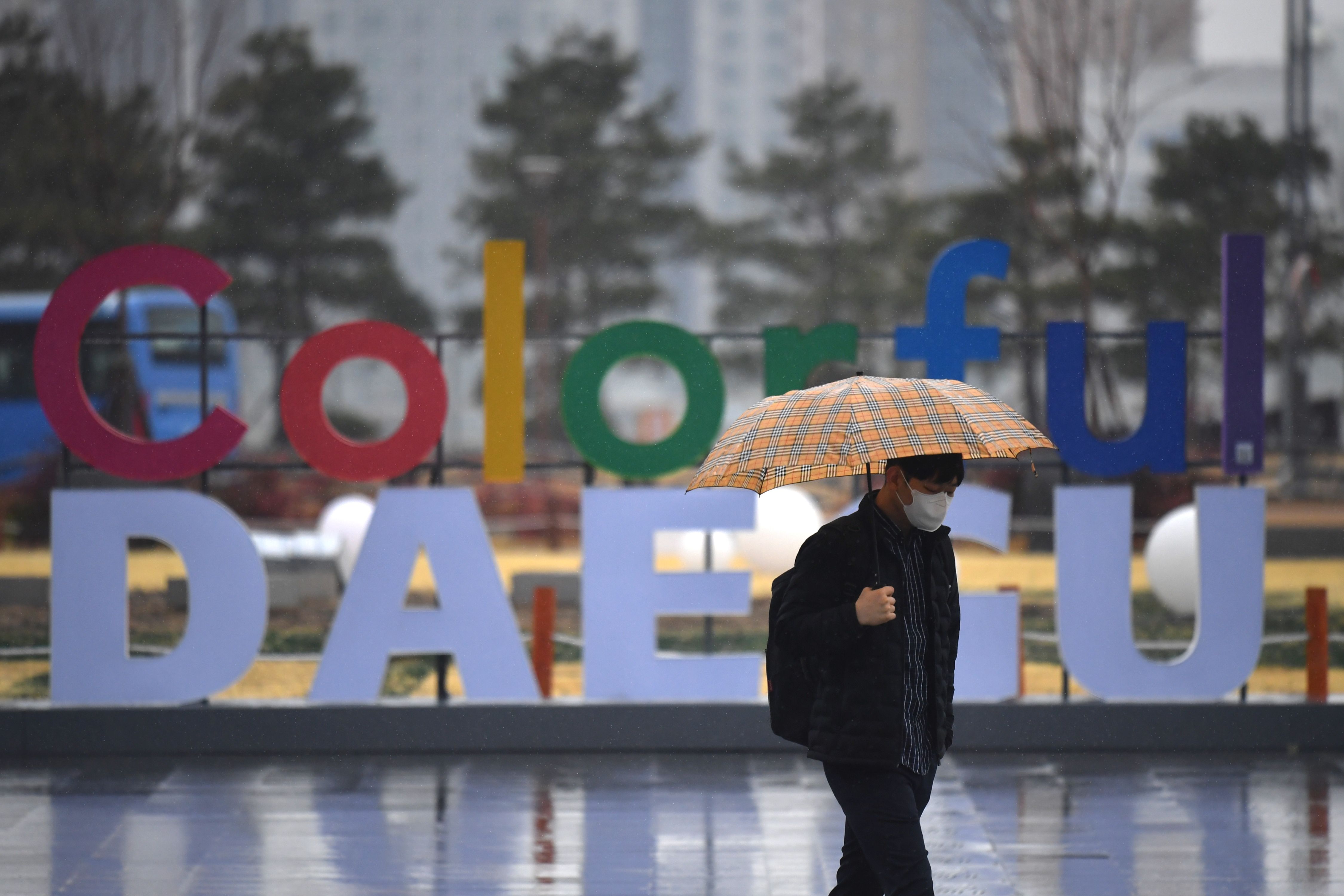 Seorang pria menggunakan masker berjalan di depan stasiun kereta di Daegu, Korea Selatan.