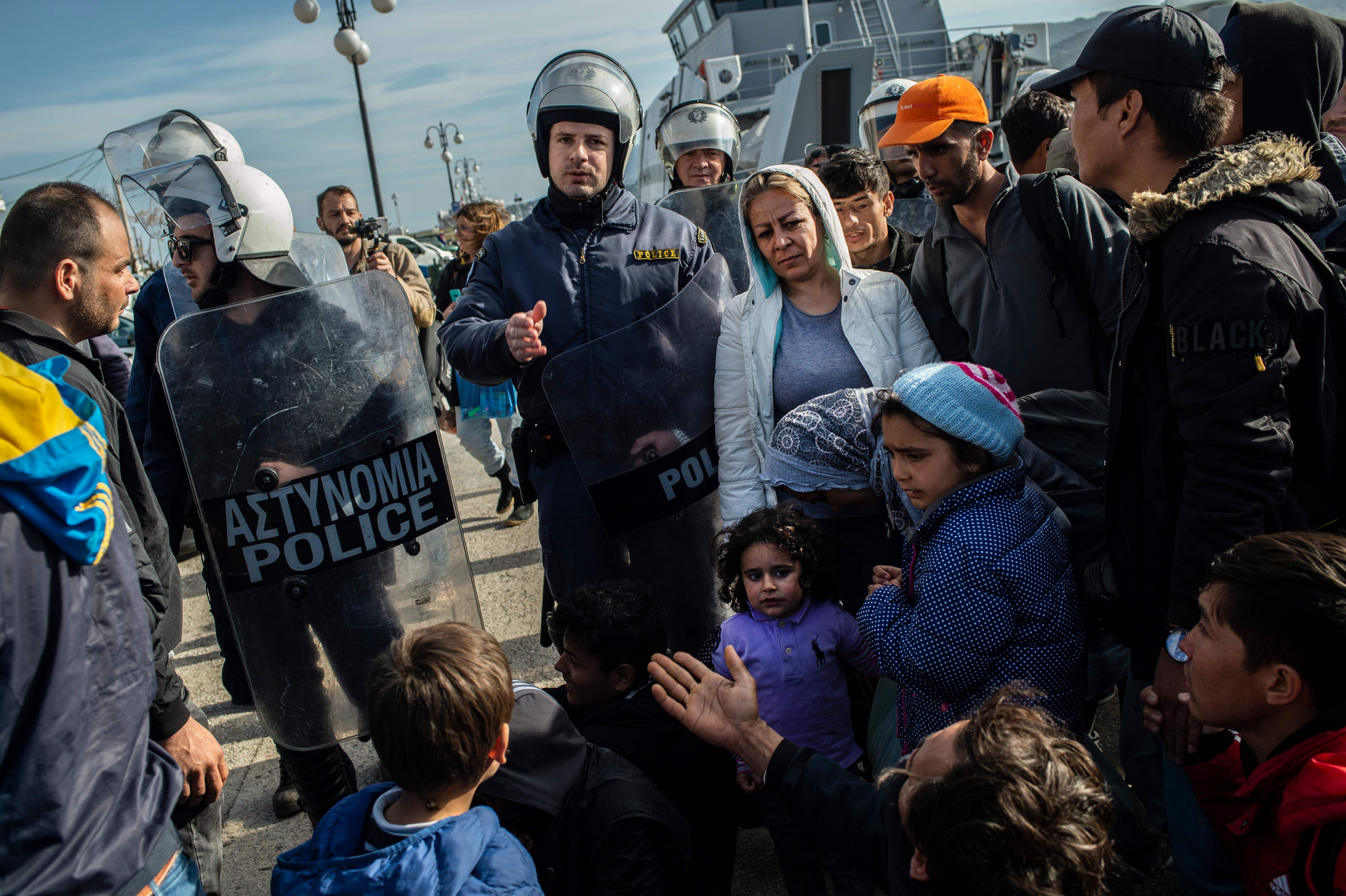 Polisi antihuru-hara Yunani mendorong dan mengusir para imigran yang tiba di pelabuhan Pulau Lesbos.