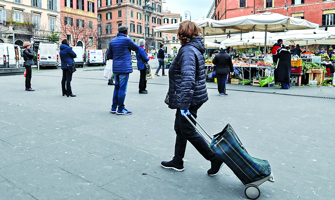  Warga mengambil jarak saat antre berbelanja sayur-sayuran dan buah-buahan di Plazza San Casimato, Trastevere, pusat Kota Roma, Italia.