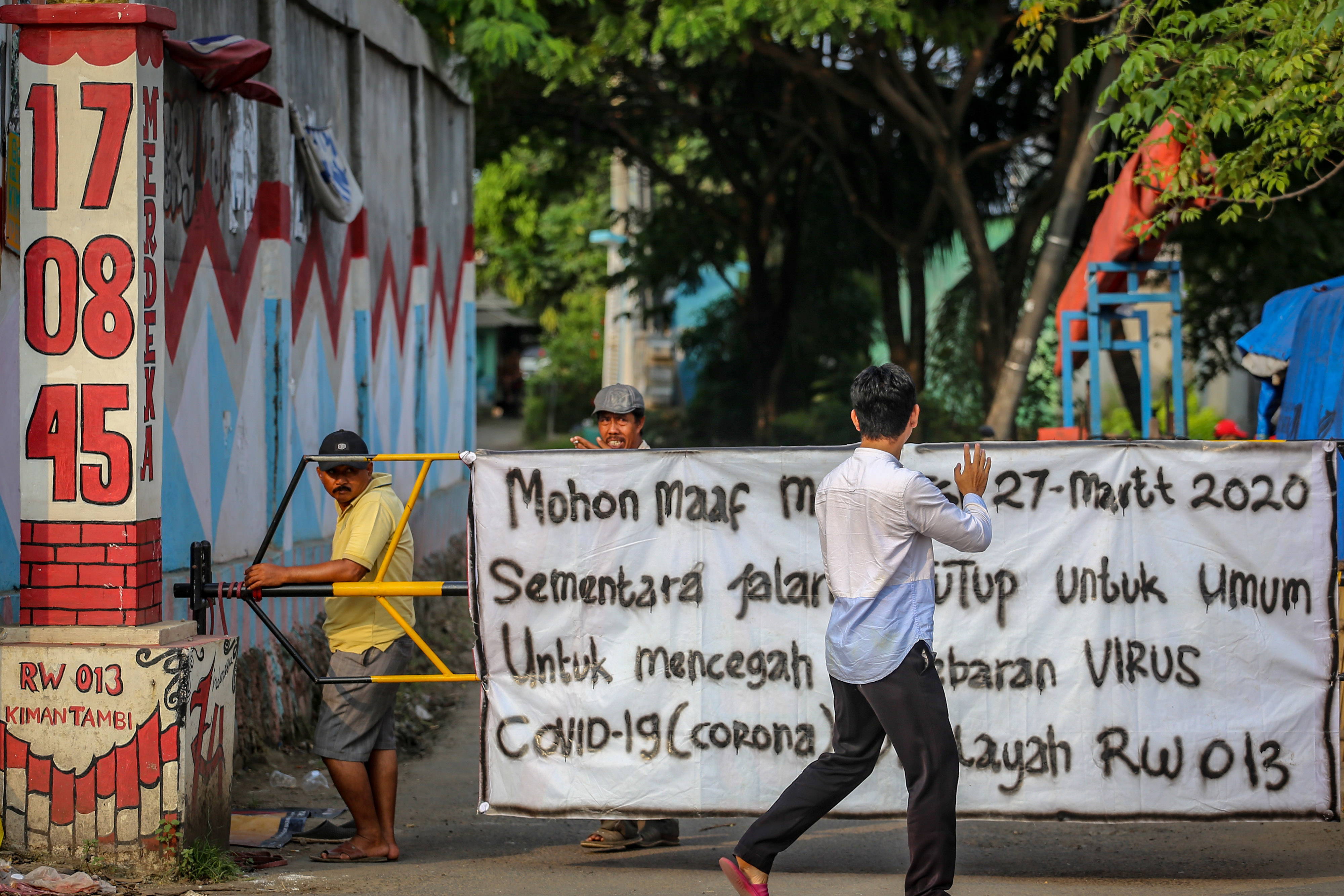 Warga berkativitas di depan akses masuk kampung yang ditutup di Kalideres, Jakarta, Sabtu (28/3/2020)