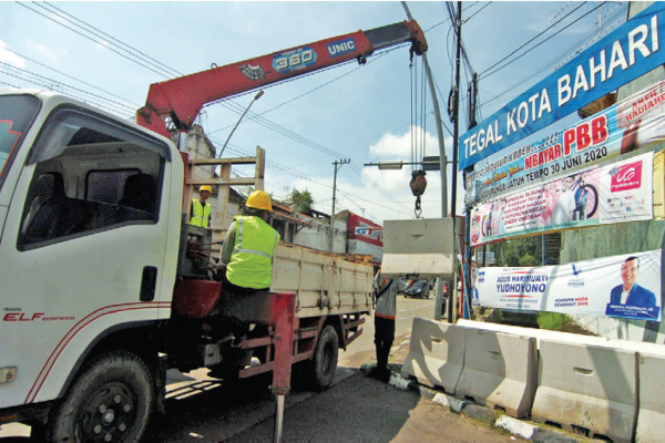 Pekerja menurunkan beton movable concrete barrier (MBC) guna penutupan jalan di jalur pantura Jl Gajah Mada, Tegal, Jawa Tengah, kemarin