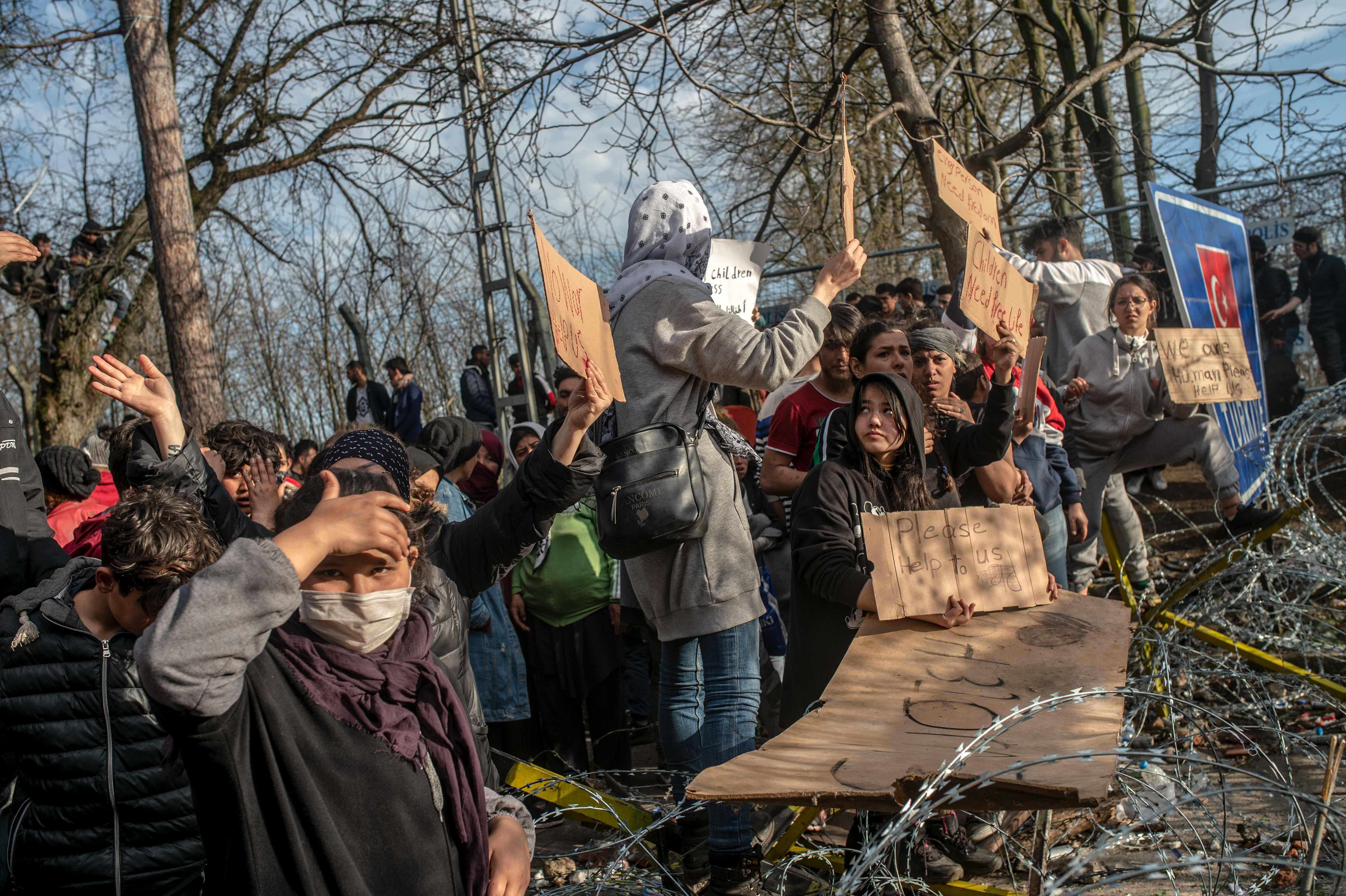 Sembari menunggu di zona penyangga dekat perbatasan Yunani, sejumlah imigran memegang selebaran unjuk rasa.