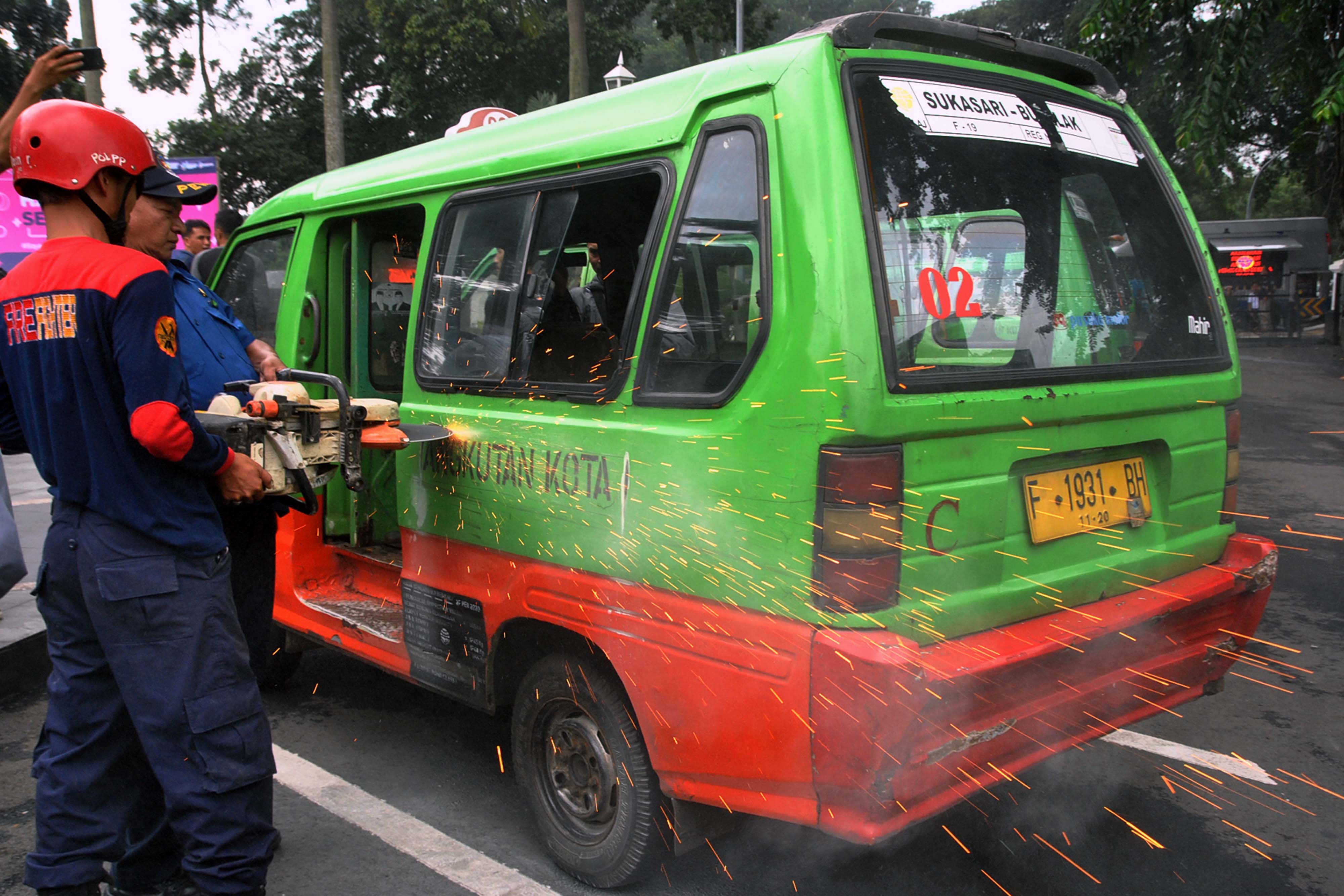  Petugas Damkar Kota Bogor memotong bagian mobil angkutan kota (angkot) saat proses reduksi atau pengurangan angkot di Plaza Balaikota Bogor