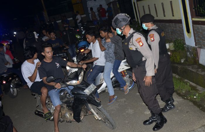 Petugas kepolisian membubarkan warga yang berkumpul di pinggir jalan di Kabupaten Gowa, Sulawesi Selatan, Minggu (29/3)