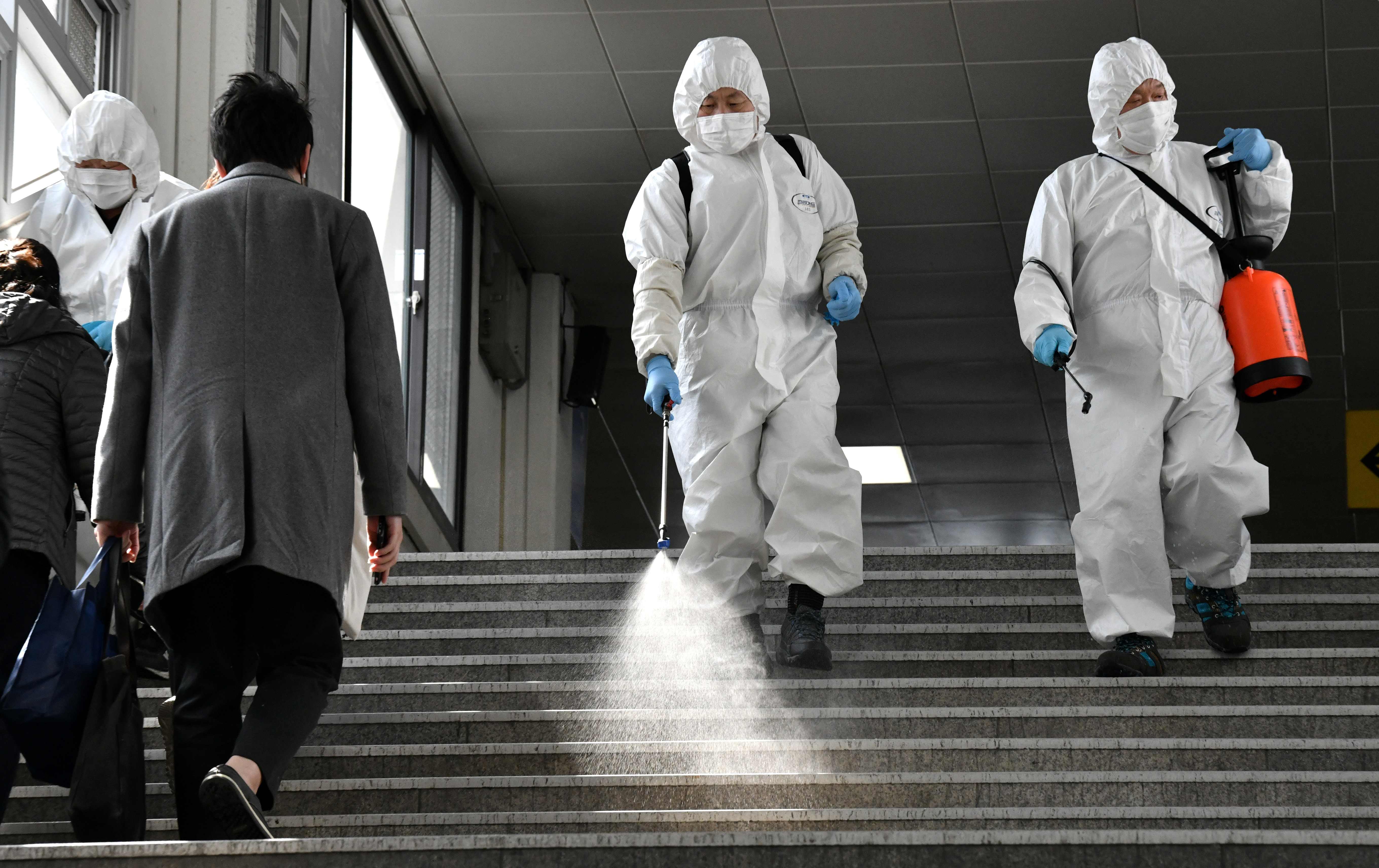 Pekerja menggunakan pakaian pelindung menyiram disinfektan di sebuah stasiun kereta di Seoul, Korea Selatan.