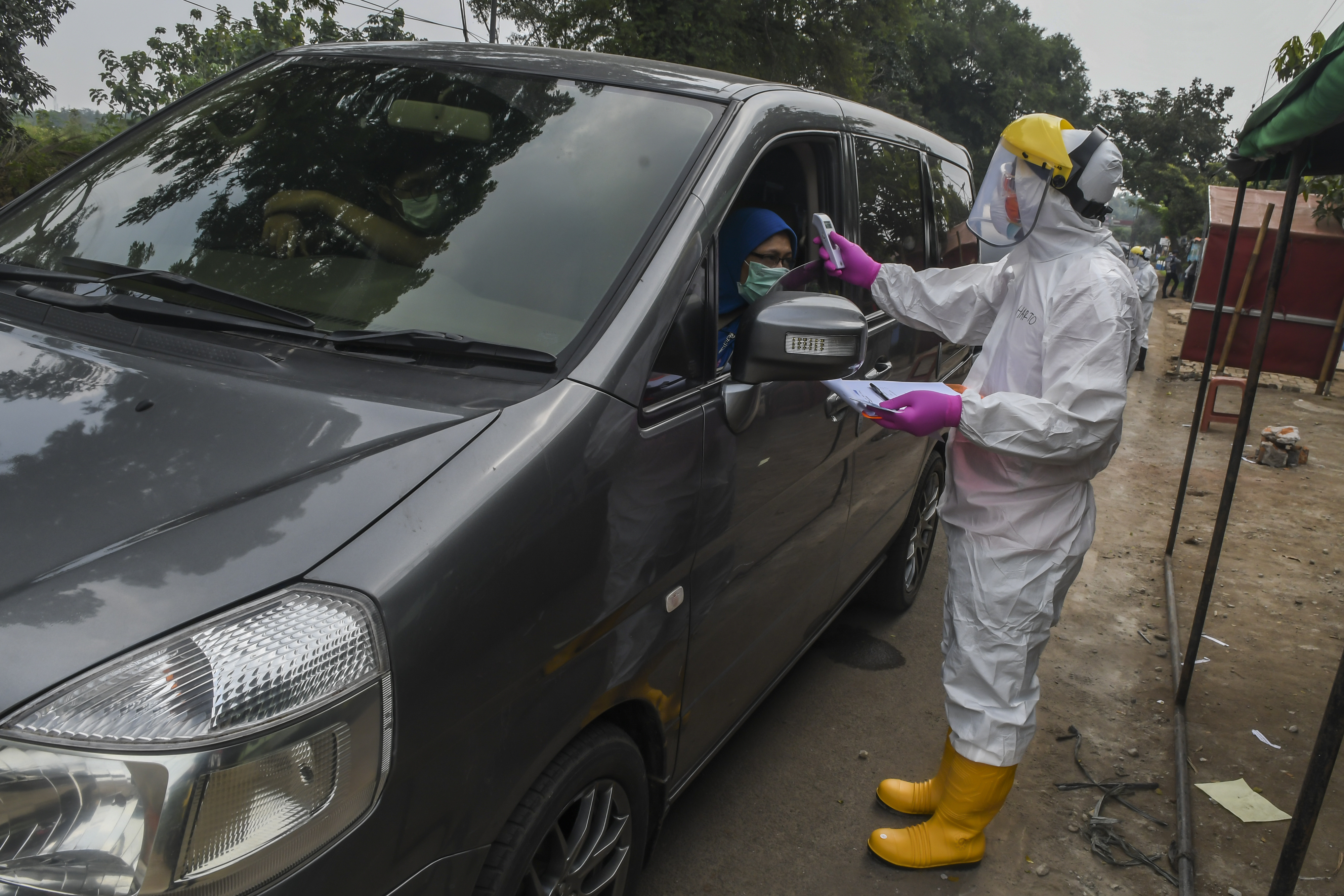 Petugas Dinas Kesehatan Kota Depok memeriksa suhu pengendra mobil saat rapid test sistem 