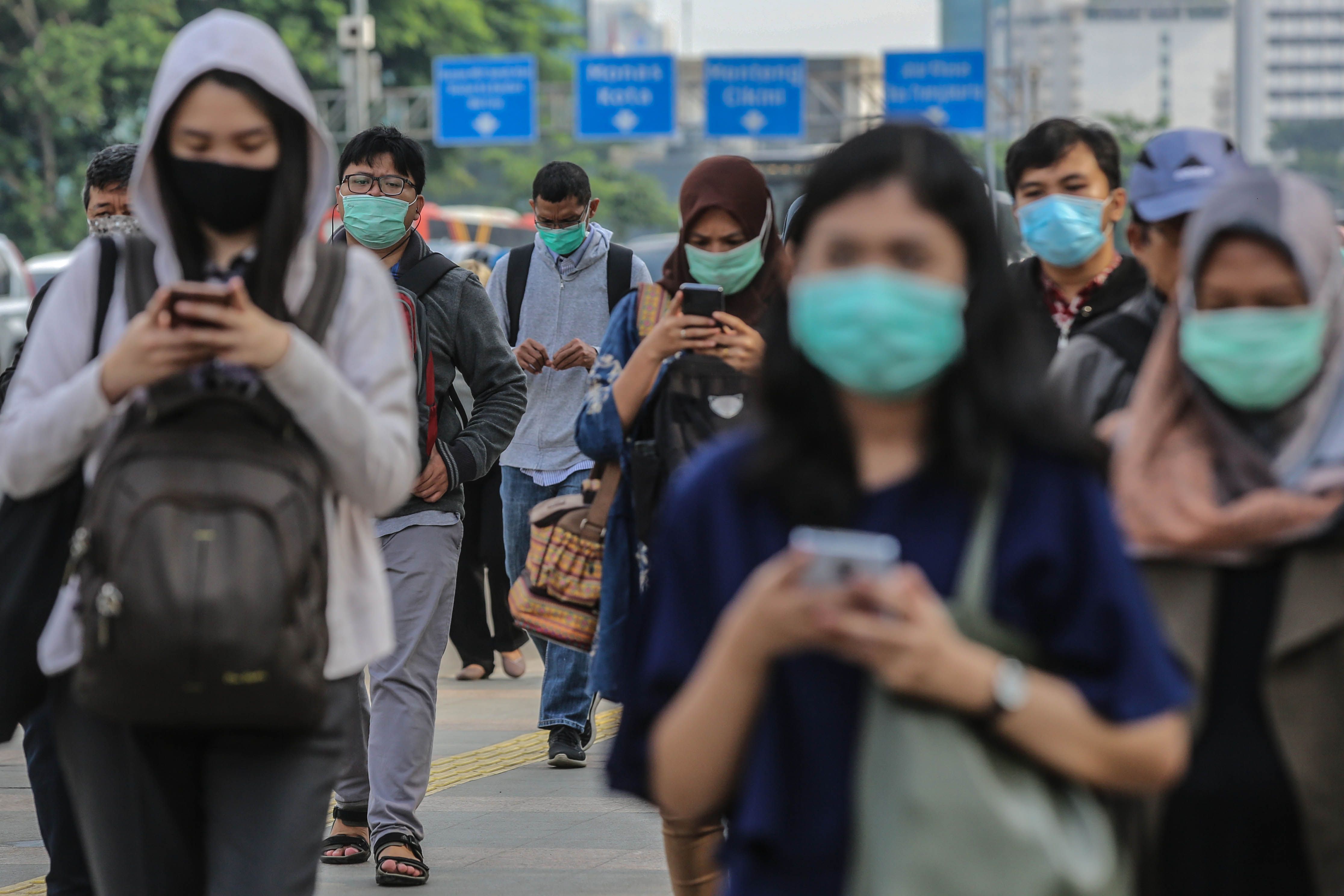Pekerja menggunakan masker saat melintasi jalur pedestrian di kawasan Sudirman, Jakarta.